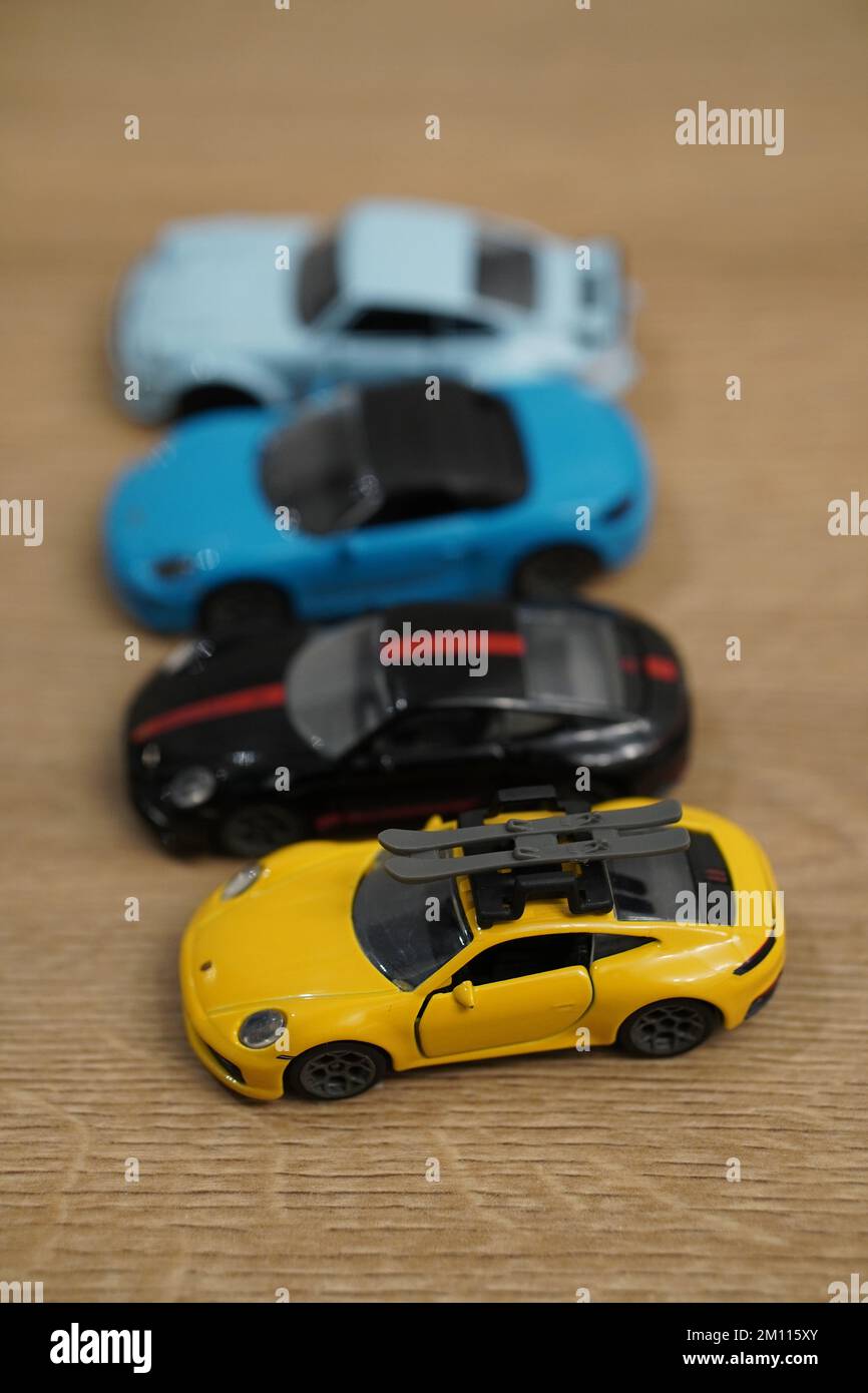 Eine vertikale Aufnahme kleiner Porsche-Automodelle der Marke Majorette auf einer Holzfläche Stockfoto