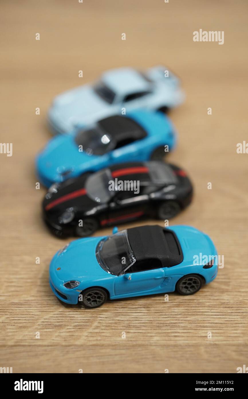 Eine vertikale Aufnahme kleiner Porsche-Automodelle der Marke Majorette auf einer Holzfläche Stockfoto