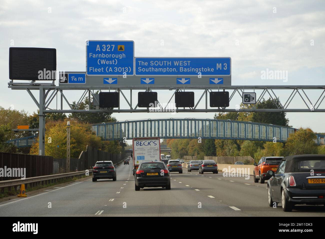 Eine Fahrt auf der Autobahn M3, die alle Schilder für ankommende Abzweigungen zu verschiedenen Orten zeigt, die Schilder sind hoch oben an den Gantry. Stockfoto