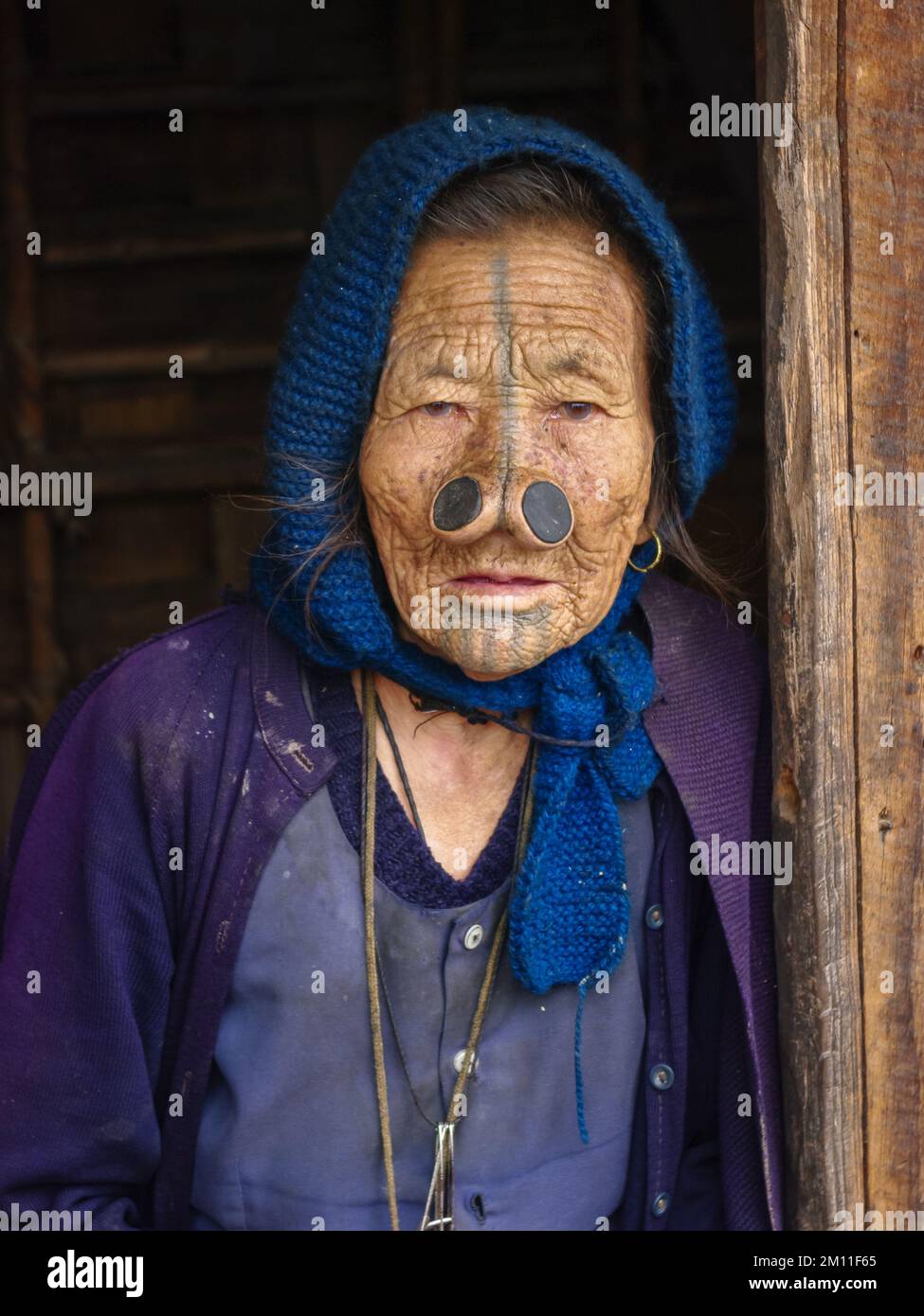 Ziro, Arunachal Pradesh, Indien - 02 24 2009 : Porträt der alten Apatani-Stammesfrau mit traditionellen Gesichts-Tattoos und Nasenstöpseln mit blauem Schal Stockfoto