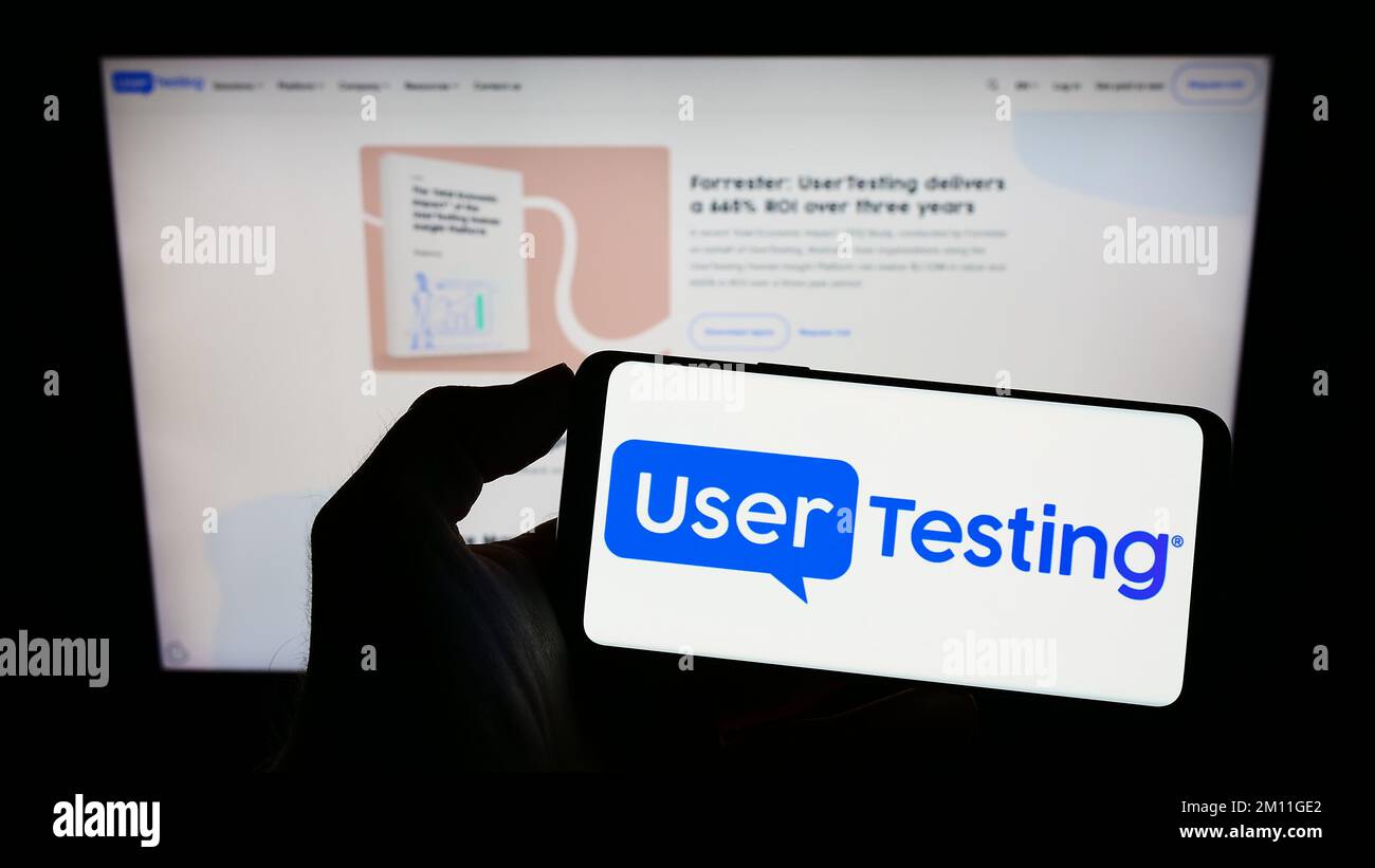 Person, die ein Mobiltelefon mit dem Logo des amerikanischen Customer-Experience-Unternehmens UserTesting Inc. Auf dem Bildschirm vor der Webseite hält. Konzentrieren Sie sich auf das Display des Telefons. Stockfoto