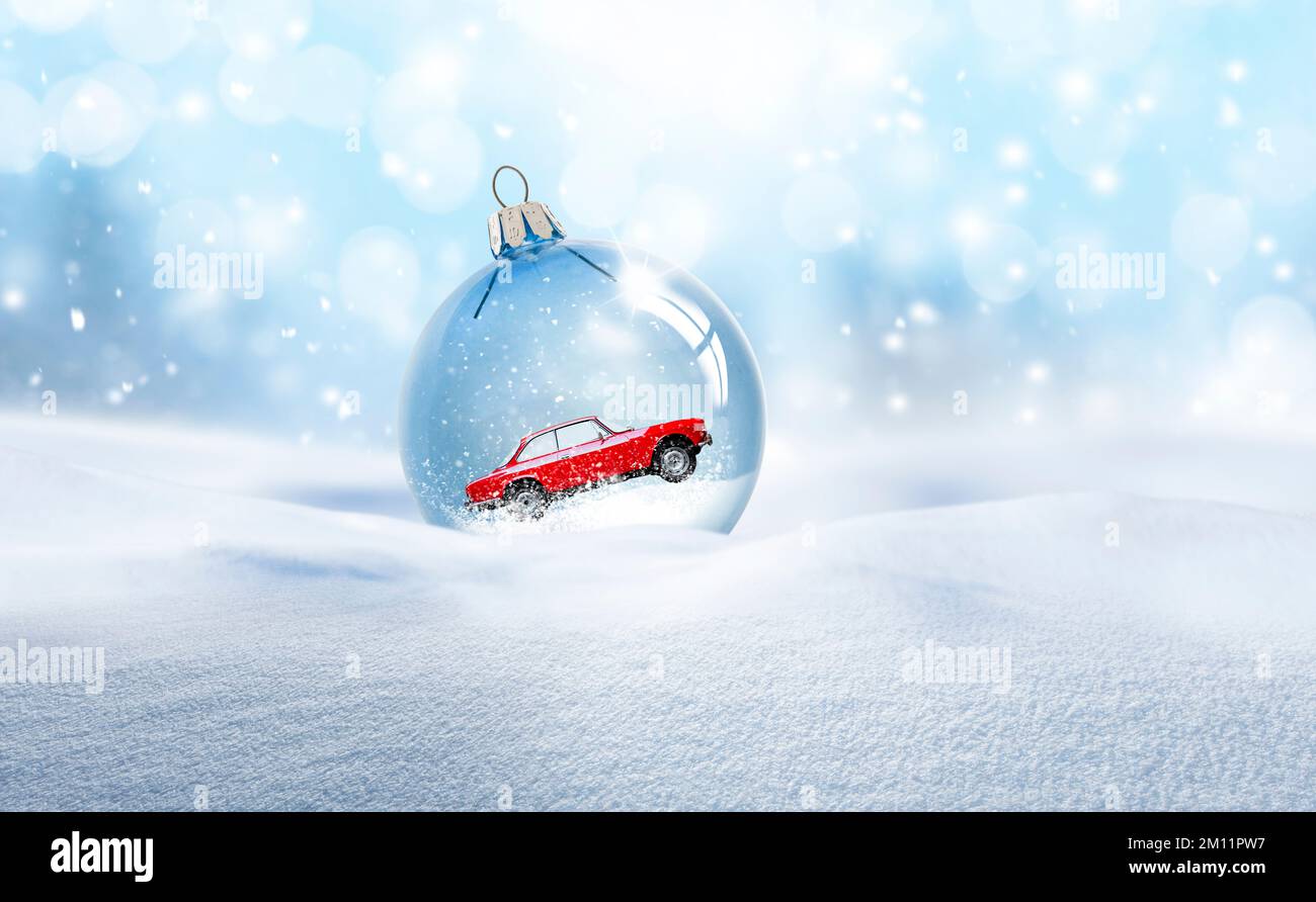 Weihnachtsball aus transparentem Glas mit einem roten Auto im Schnee Stockfoto