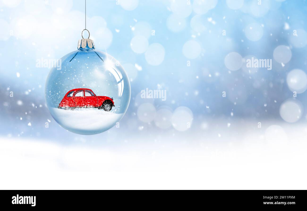 Weihnachtsball aus transparentem Glas mit einem roten Auto im Schnee Stockfoto