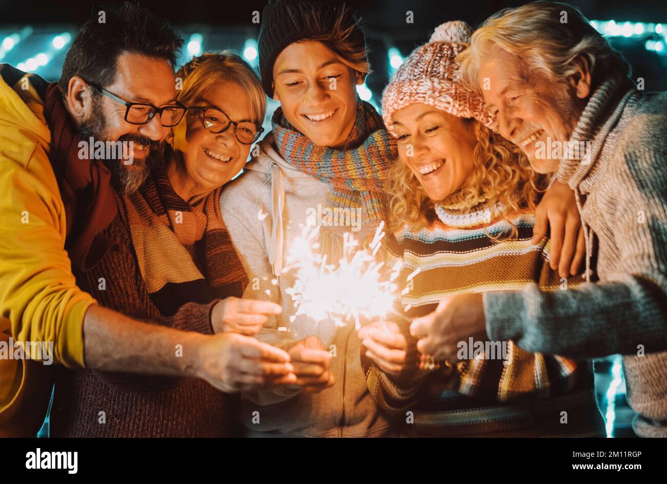 Farbenfrohes Bild einer Gruppe von Familienmitgliedern von jung bis erwachsen und reif haben Spaß in Freundschaft mit Glitzerlicht während der weihnachtszeit und am nächsten Abend. Fröhliche Leute in ihrer Freizeit Stockfoto