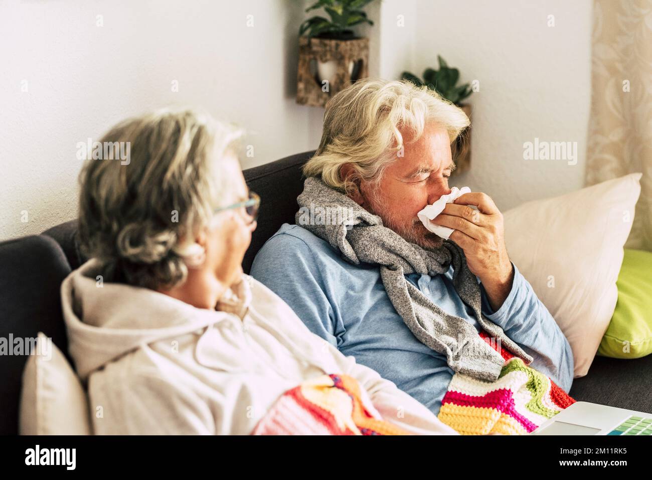 Zwei Personen Mann und Frau im Alter mit Grippe-Symptome bei der Heilung und gegenseitig helfen. Seniorenpaar mit Erkältung und Virusinfektion, das auf dem Sofa sitzt. Kalte Temperatur im Haus für Energie Stockfoto