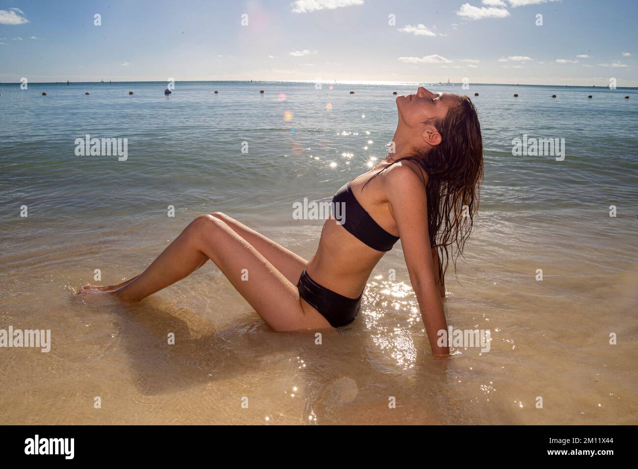 Junges weibliches Model in sexy Badebekleidung, posiert an einem der Strände der Insel Mauritius im Sonnenlicht. Pertfect wellige Haare, brauner, feiner Körper. Tropische Sommerstimmung. Stockfoto