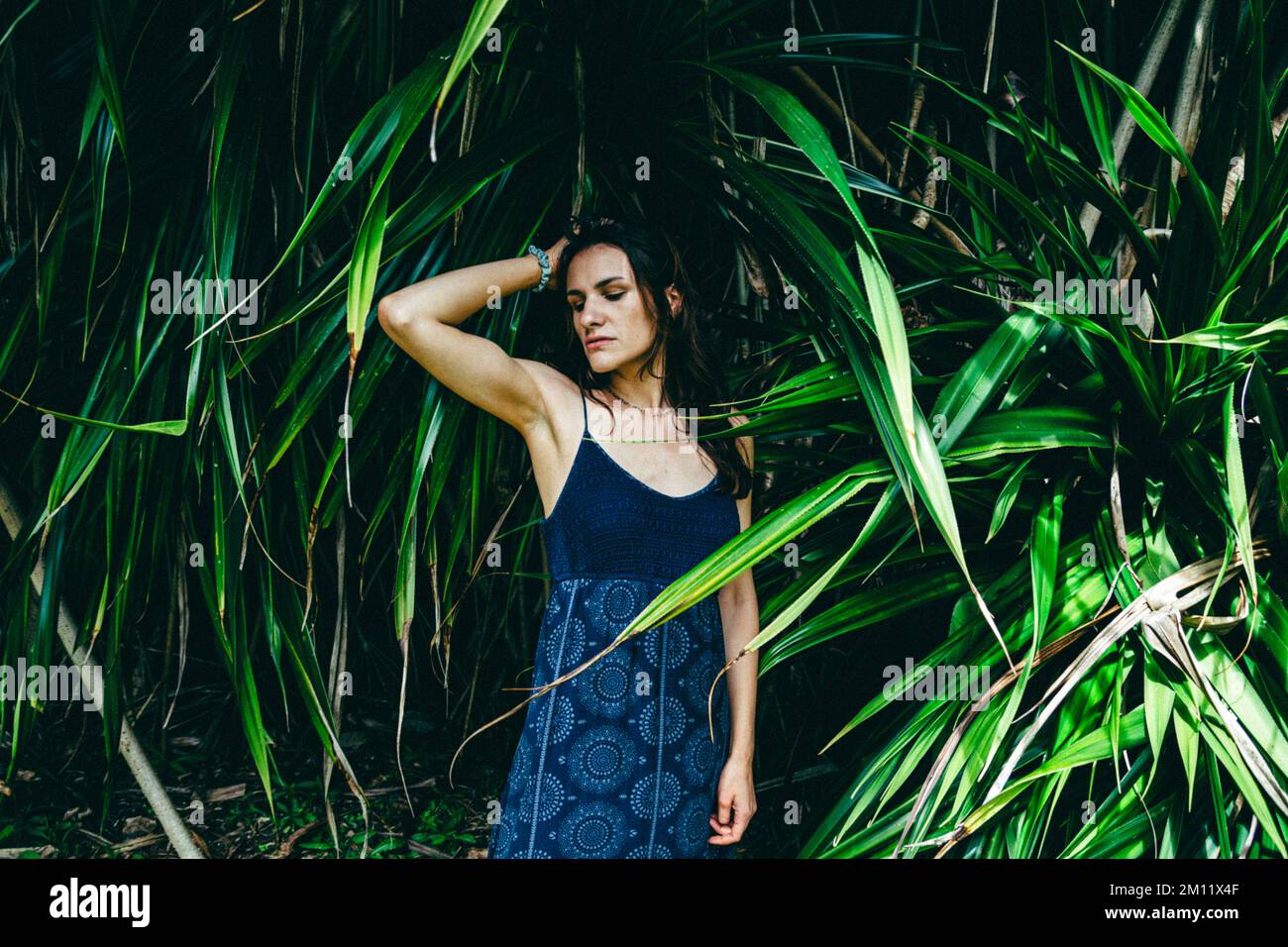 Junges weibliches Modell, umgeben vom natürlichen Hintergrund aus Palmenblättern Stockfoto