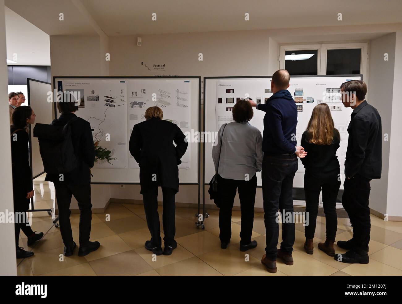 09. Dezember 2022, Thüringen, Weimar: Gäste der Preisverleihung für den Architekturwettbewerb zur Restaurierung des historischen Hauses von Johann Wolfgang von Goethe in Übereinstimmung mit der Erhaltungsanordnung und dem neuen Museumskonzept betrachten die preisgekrönten Designs. Drei Architekturbüros mit ihren Entwürfen stehen auf der Auswahlliste. Das Siegerdesign soll Ende Februar bekannt gegeben werden. Das Ensemble ist Teil des Goethe-Nationalmuseums, ist ein denkmalgeschütztes Gebäude und gehört zum UNESCO-Weltkulturerbe. Im Zuge der für 2026 geplanten Renovierung soll das Wohngebäude in der Werbung erscheinen Stockfoto