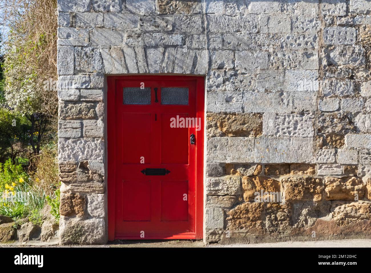 England, Dorset, Abbotsbury, Red Doorway und Traditional Stone Building Stockfoto