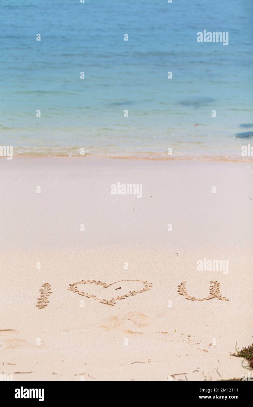 Ich liebe dich - wie eine Nachricht mit einem Finger im Sand geschrieben an einem Strand mit Wellen und blauem Ozean auf Mauritius Island, Afrika, Draufsicht, niemand Stockfoto