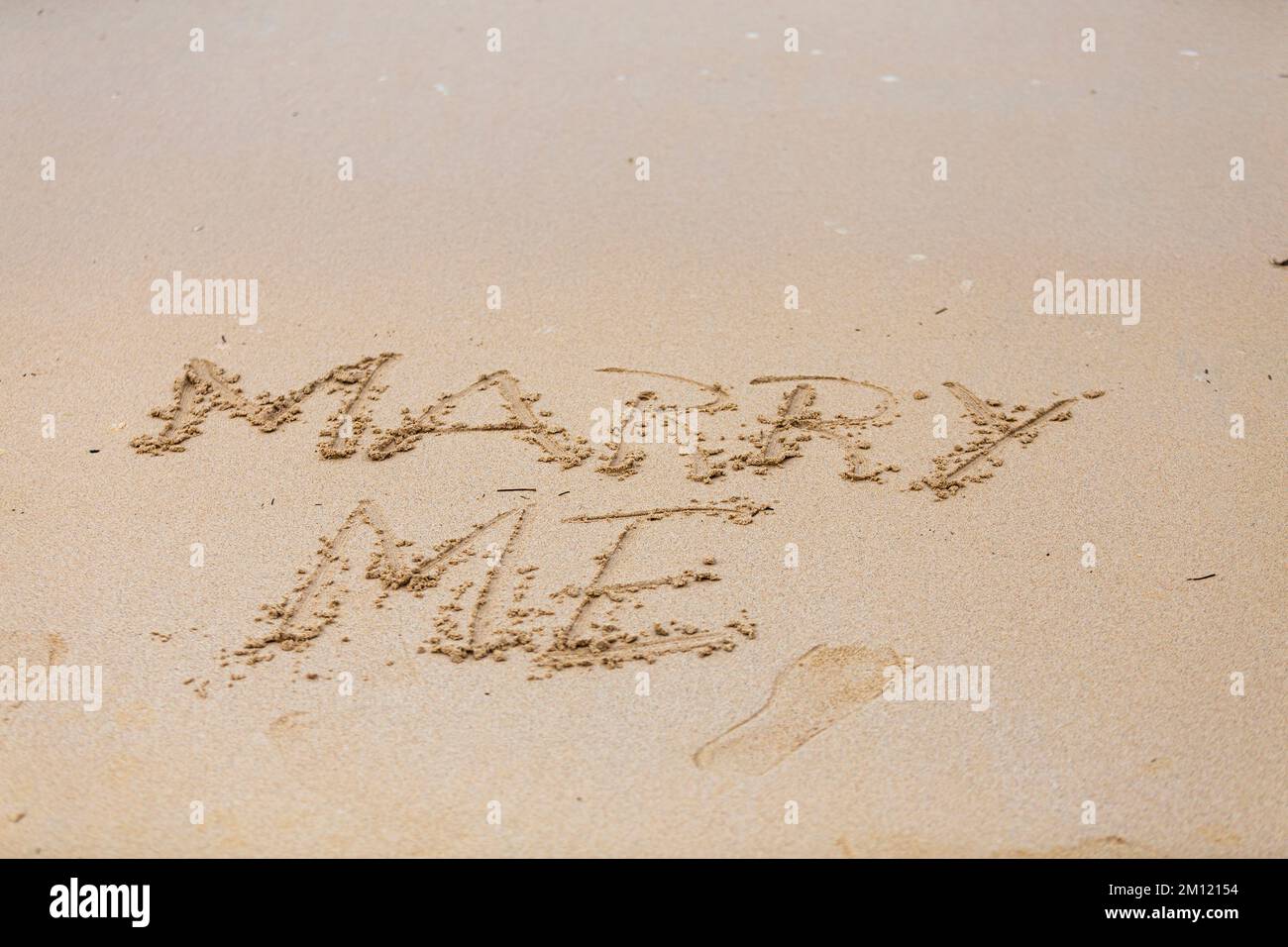 Heirate mich - wie eine Nachricht geschrieben mit einem Finger im Sand an einem Strand mit Wellen und blauem Ozean auf Mauritius Island, Afrika, Draufsicht, niemand Stockfoto