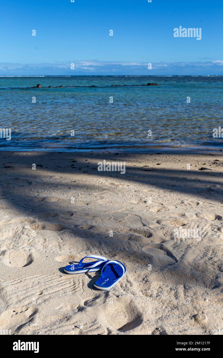 Flip-Flops oder Sandalen für Frauen am Sandstrand an der Küste mit Effekt, dass die Sonne auf dem Meer untergeht. Tourismus Entspannen Reisen Sie im tropischen Sommer im Urlaub oder das Konzept des gebrochenen Herzens. Bild mit freiem Speicherplatz. Stockfoto