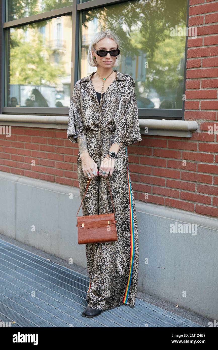 MAILAND, ITALIEN - 21. SEPTEMBER 2022: Frau mit Overall aus Leopardenfell und brauner Ledertasche vor der Fendi-Modenschau, Mailand Fashion Week Street Style Stockfoto