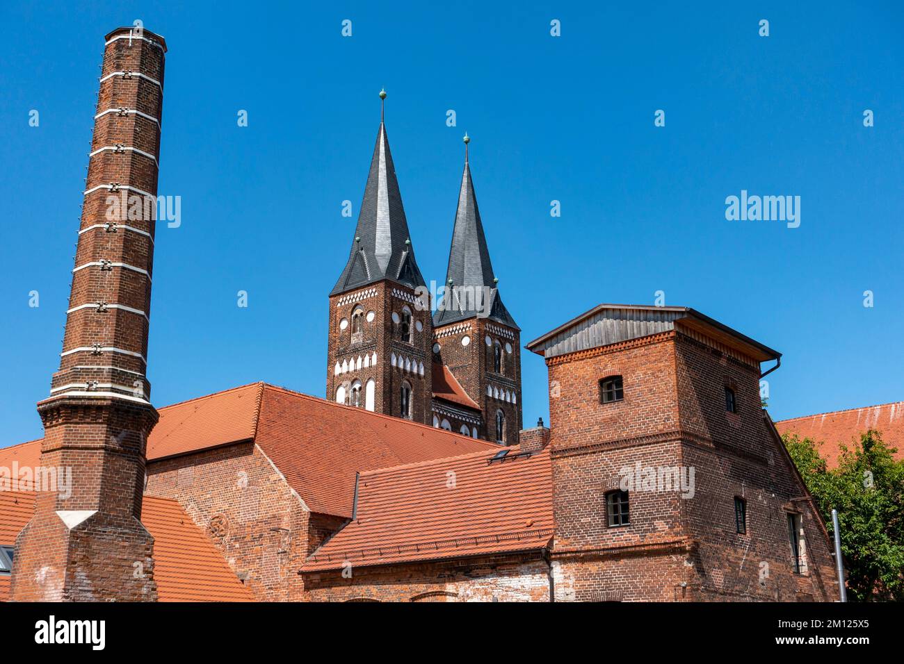 Der Doppelturm der Kollegialkirche Marien und Nikolaus, der kommerzielle Bau und der Kamin der ehemaligen Brennerei. Stockfoto