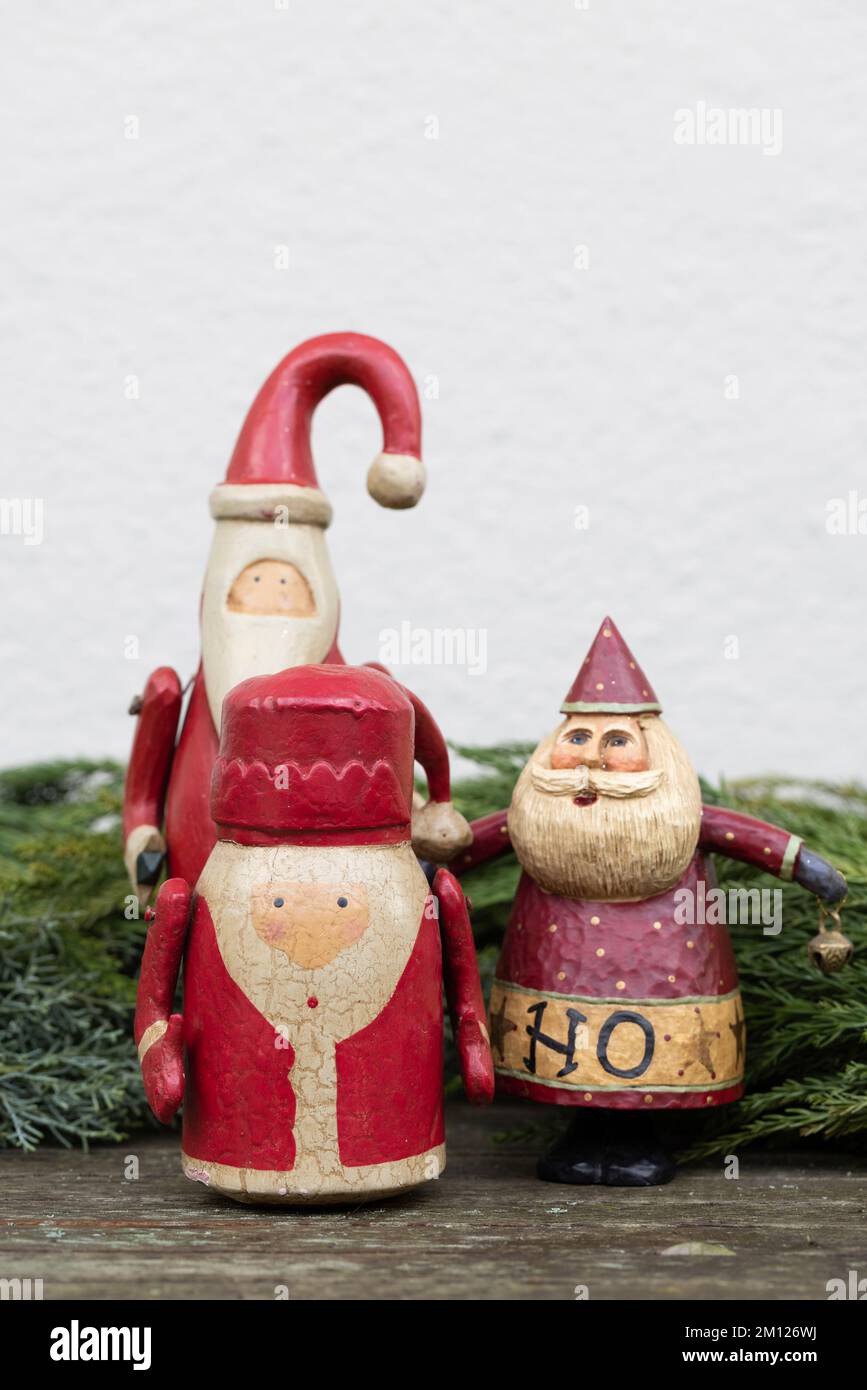 Drei altmodische Weihnachtsmann-Figuren vor Tannengrün Stockfoto