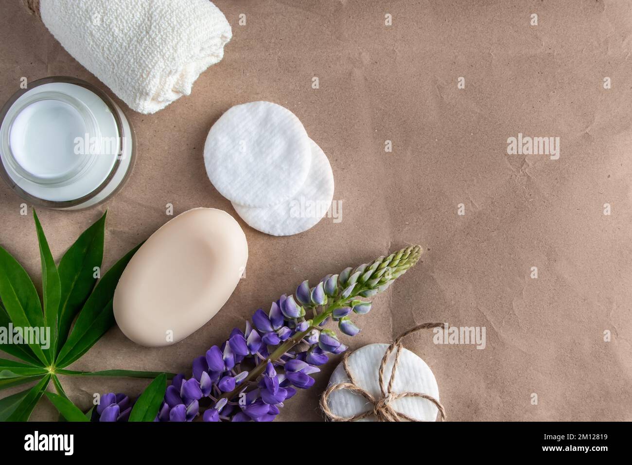 Natürliche Bio-Kosmetik und Lupine Blumen auf Bastelpapier Hintergrund. Feuchtigkeitsspendende Creme, Seife und Handtuch. Körperpflegekonzept. Spa und Schönheitsbehandlungen Stockfoto