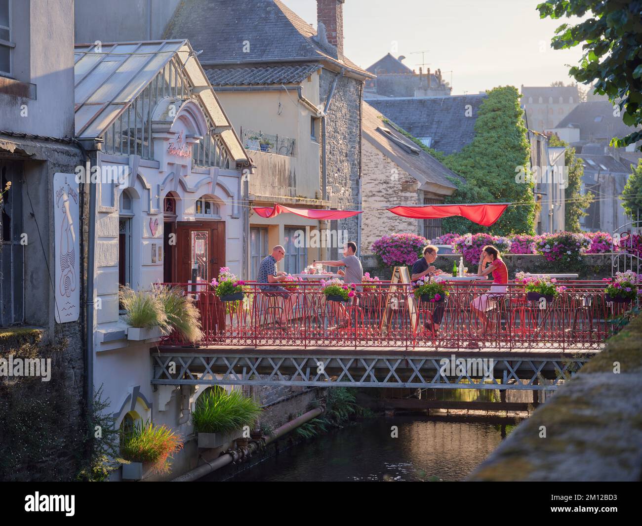 Ein Steg, auf dem Gäste eines Restaurants in der abendlichen Wärme des Sommers in Morlaix im französischen Departement Finistère unterhalten werden Stockfoto