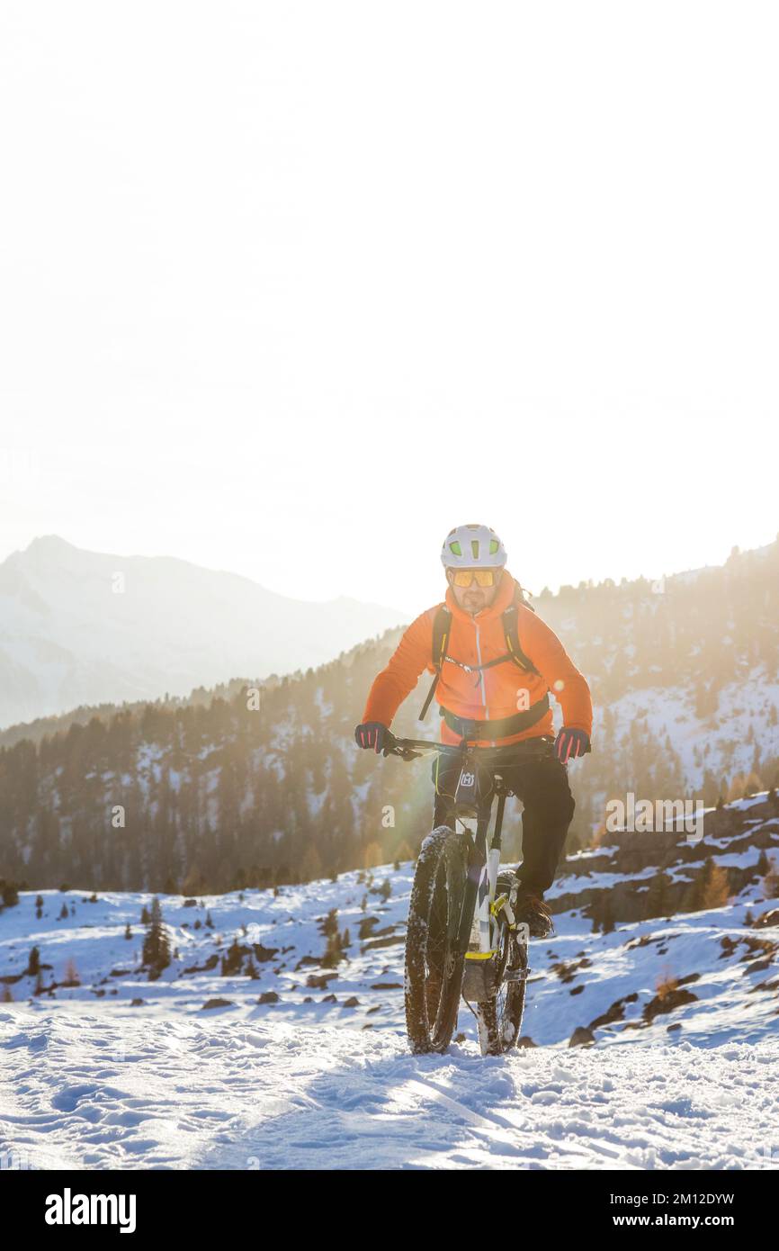 Italien, Venetien, Provinz Belluno, Dolomiten, Radfahrer, die im Winter auf einem modernen E-Bike auf einer Schneereise unterwegs sind Stockfoto