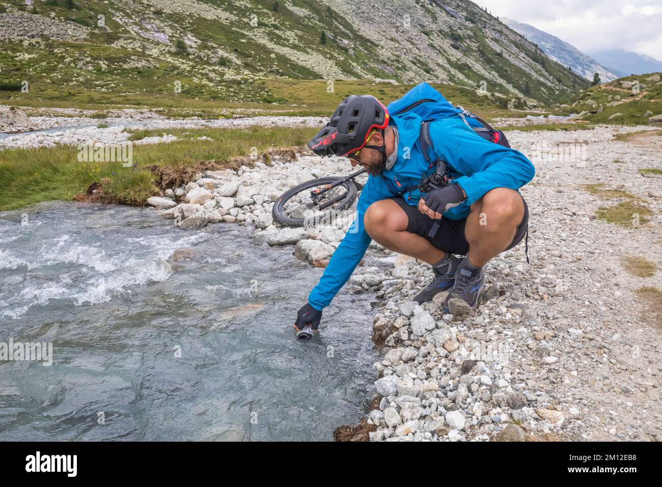 Österreich, Tirol, Zillertal, Finkenberg, man-Radfahrer machen eine Pause, um die Flasche im Pfitschergründl oder Zamsergrund mit reinem Alpenwasser zu füllen Stockfoto