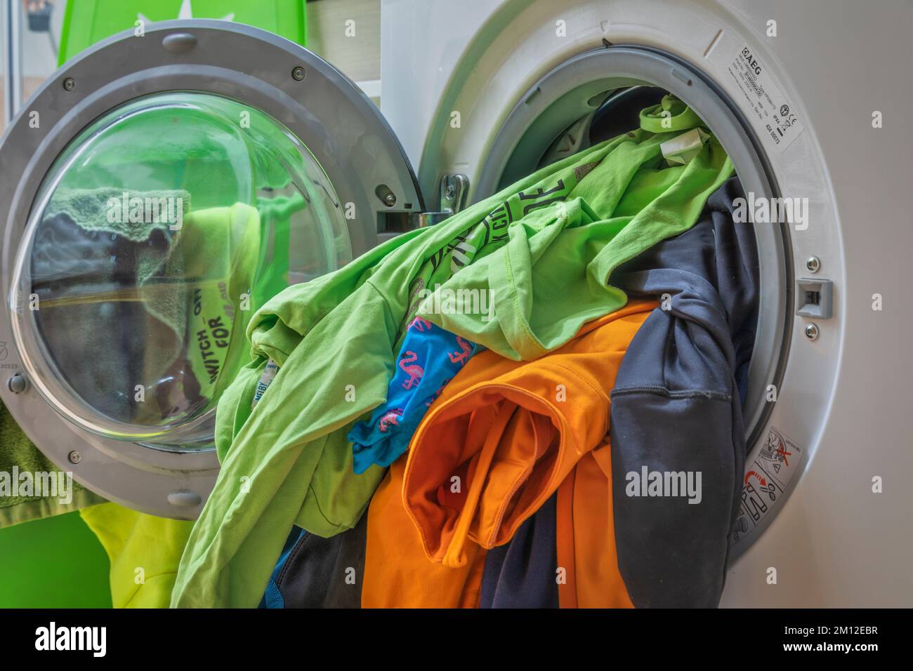 Verschmutzte Kleidung läuft von der Tür der Waschmaschine ab Stockfoto