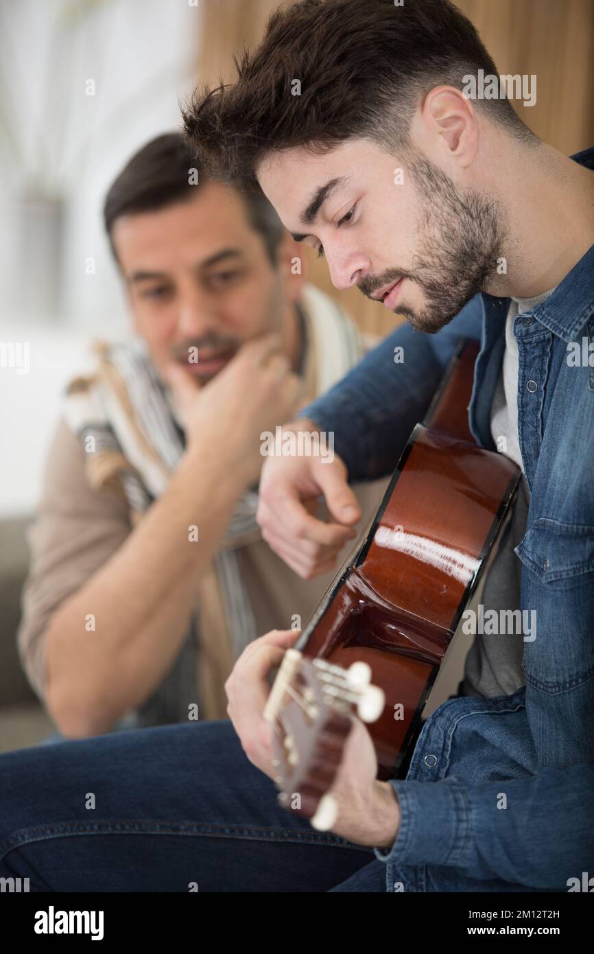 Ein Musiker, der seinem Sohn die elektrische Gitarre beibringt Stockfoto
