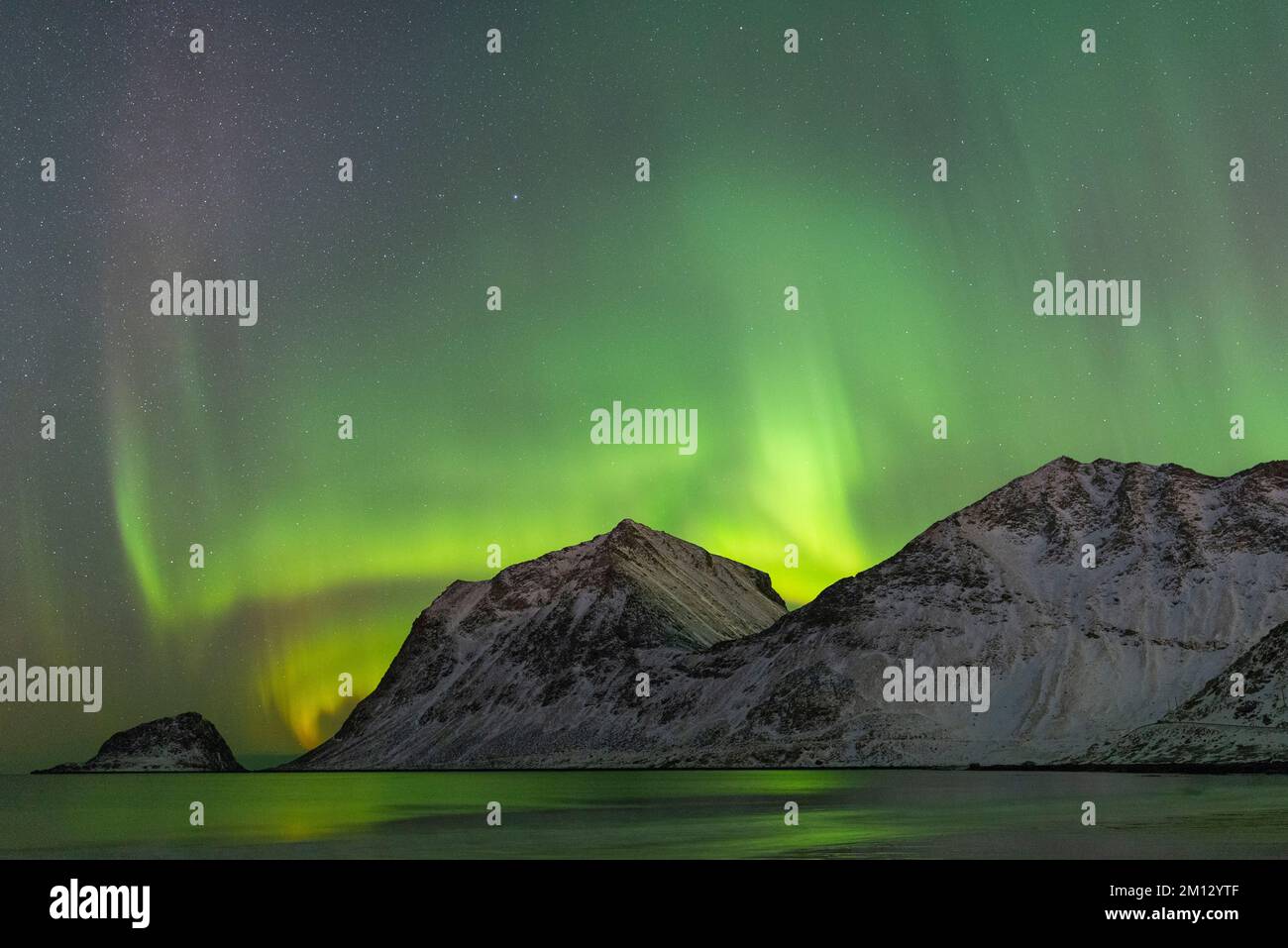 Starke aurora über den Bergen am Haukland-Strand im Winter, Lofoten Stockfoto