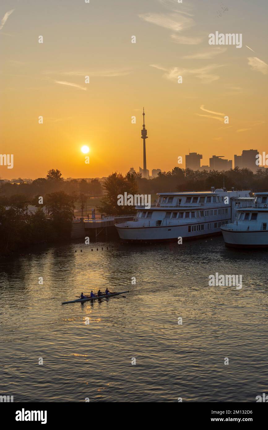 Wien, Ruderboot bei Sonnenaufgang an der Donau (Donau), Schulschiff Bertha-von-Suttner-Gymnasium, Blick auf Donauturm und Donaucity mit DC Tower 1 im Jahr 22. Donaustadt, Österreich Stockfoto