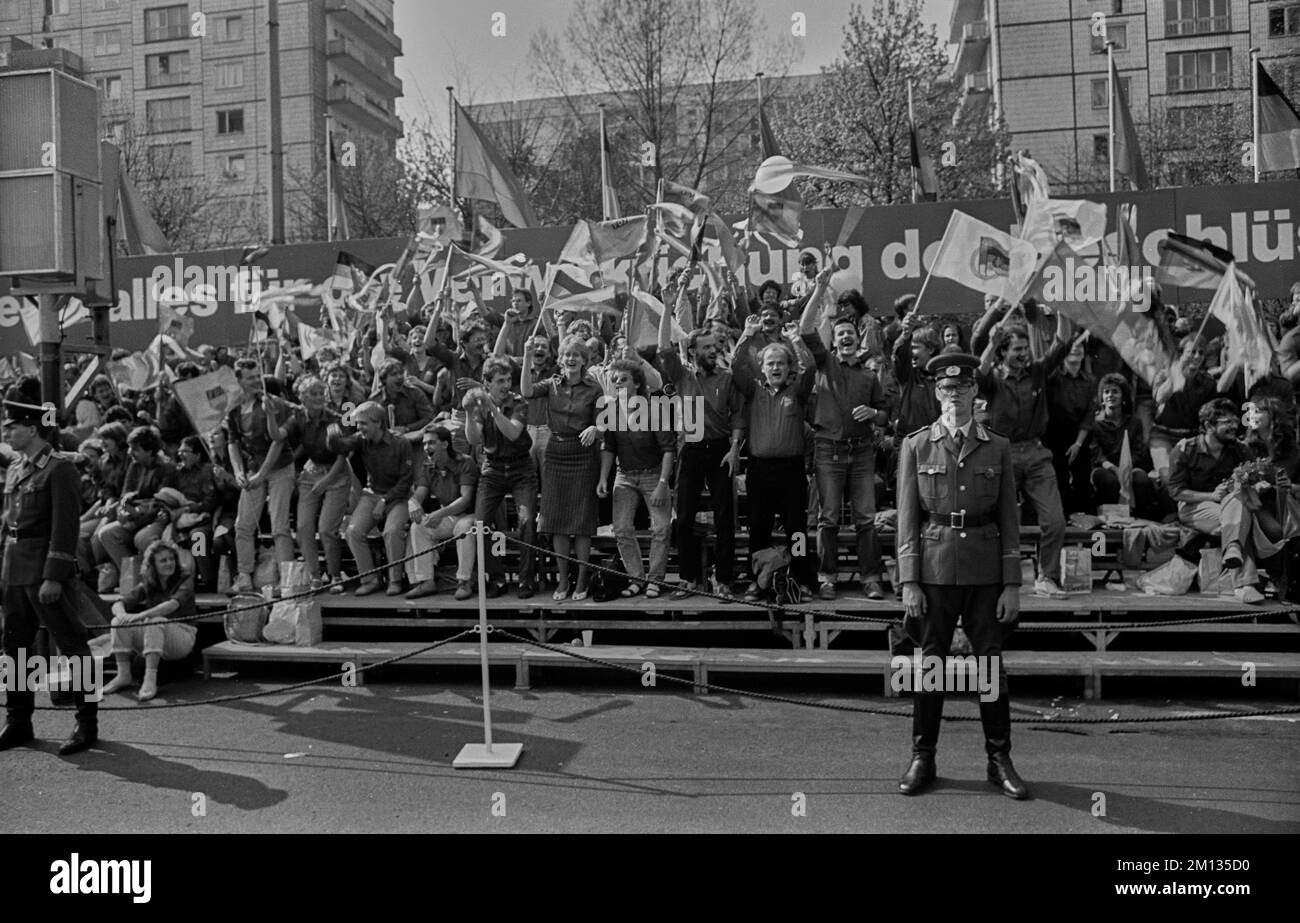 DDR, Berlin, 01.05.1988. Mai, Demonstration in Karl-Marx-Allee, jubelnde junge Kameraden, Flaggen, NVA-Soldat Stockfoto