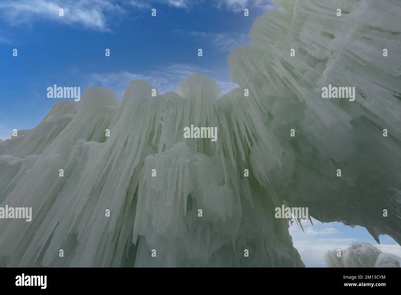 Eine imposante Mauer aus Eis und Eiszapfen kontrastierte mit einem leuchtend blauen Himmel mit Zirruswolken bei der Eisschlössershow in Lake Geneva, Wisconsin, Stockfoto