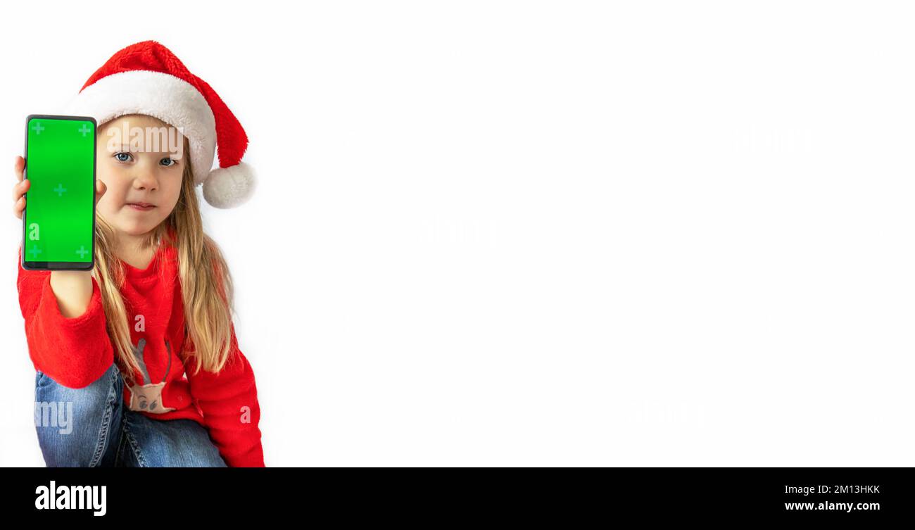 Weihnachten. Ein Mädchen mit weihnachtsmann-Hut, das ein Telefon mit grünem Bildschirm hat, Kopierraum, isolieren. Stockfoto