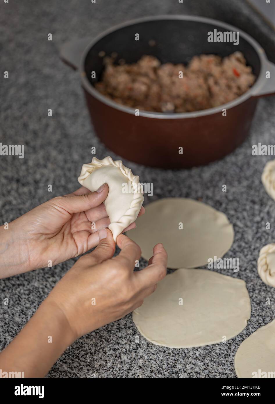 Frauenhände machen argentinische Fleischempanada. Stockfoto