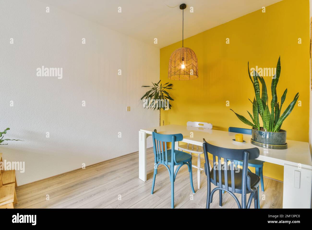 Ein Esstisch und Stühle in einem Raum mit gelben Wänden, Holzfußboden und weißen Verzierungen an den Wänden Stockfoto