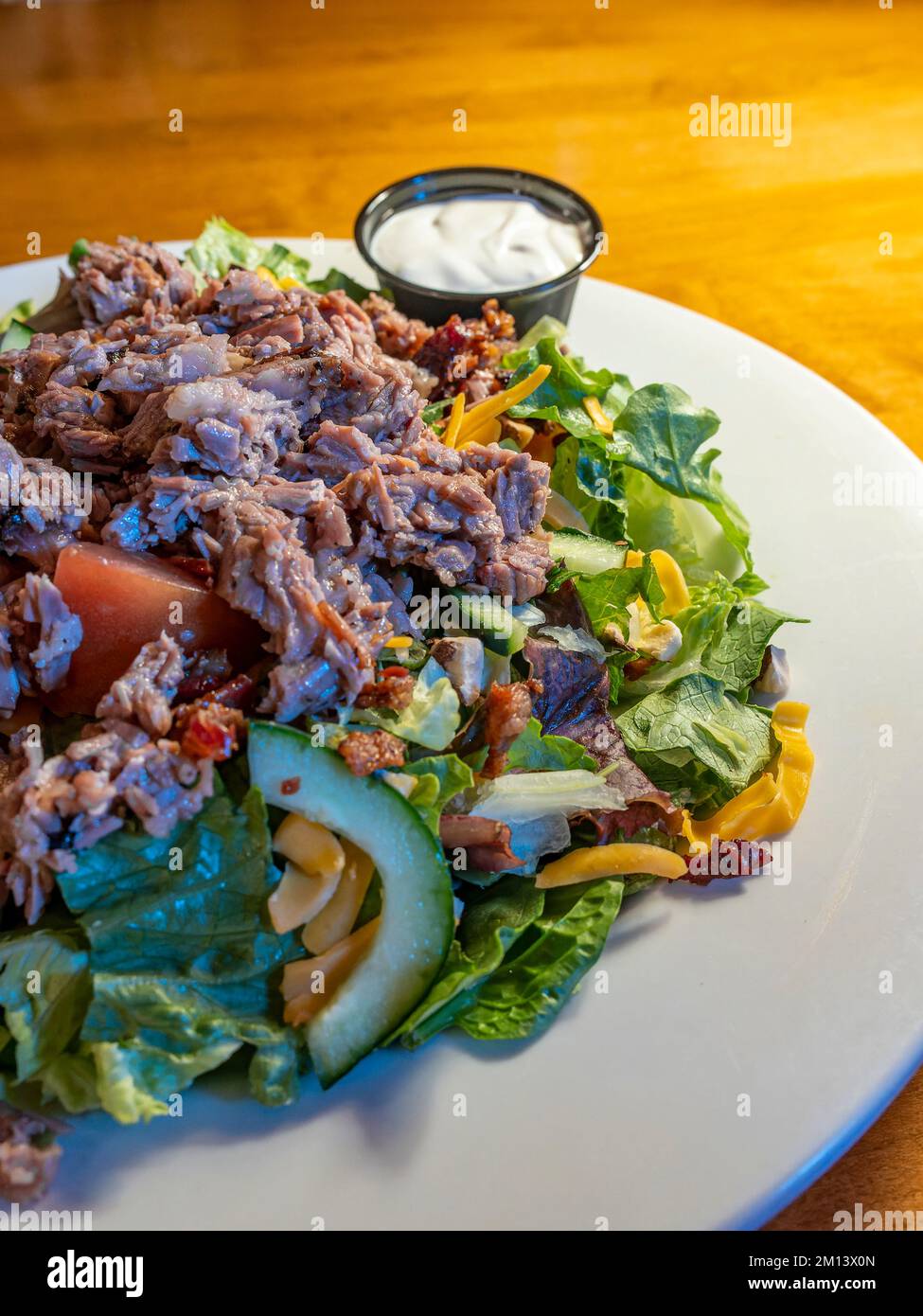 Restaurant-Lunch-Teller mit Rinderbrust über einem Gartensalat mit Dressing an der Seite. Stockfoto
