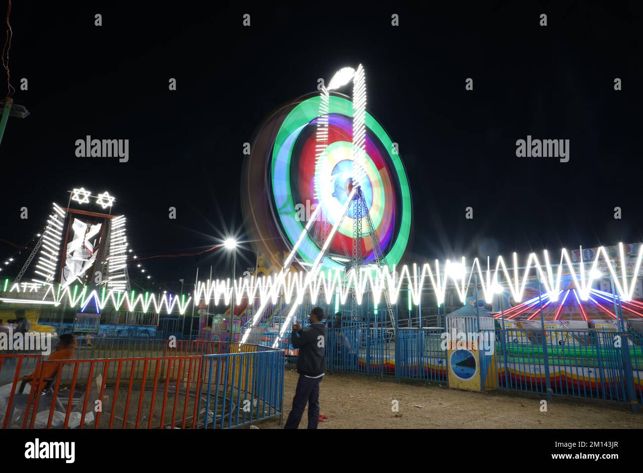 Lange Belichtung, langsame Verschlusszeit Aufnahme eines sich drehenden Riesenrads mit wunderschönen Lichtern auf der indian Fun Fair bei Nacht Stockfoto
