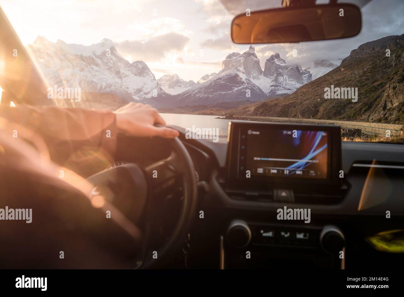 Eine Autofahrt mit der wunderschönen Landschaft eines Sees und schneebedeckten Bergen im Hintergrund Stockfoto