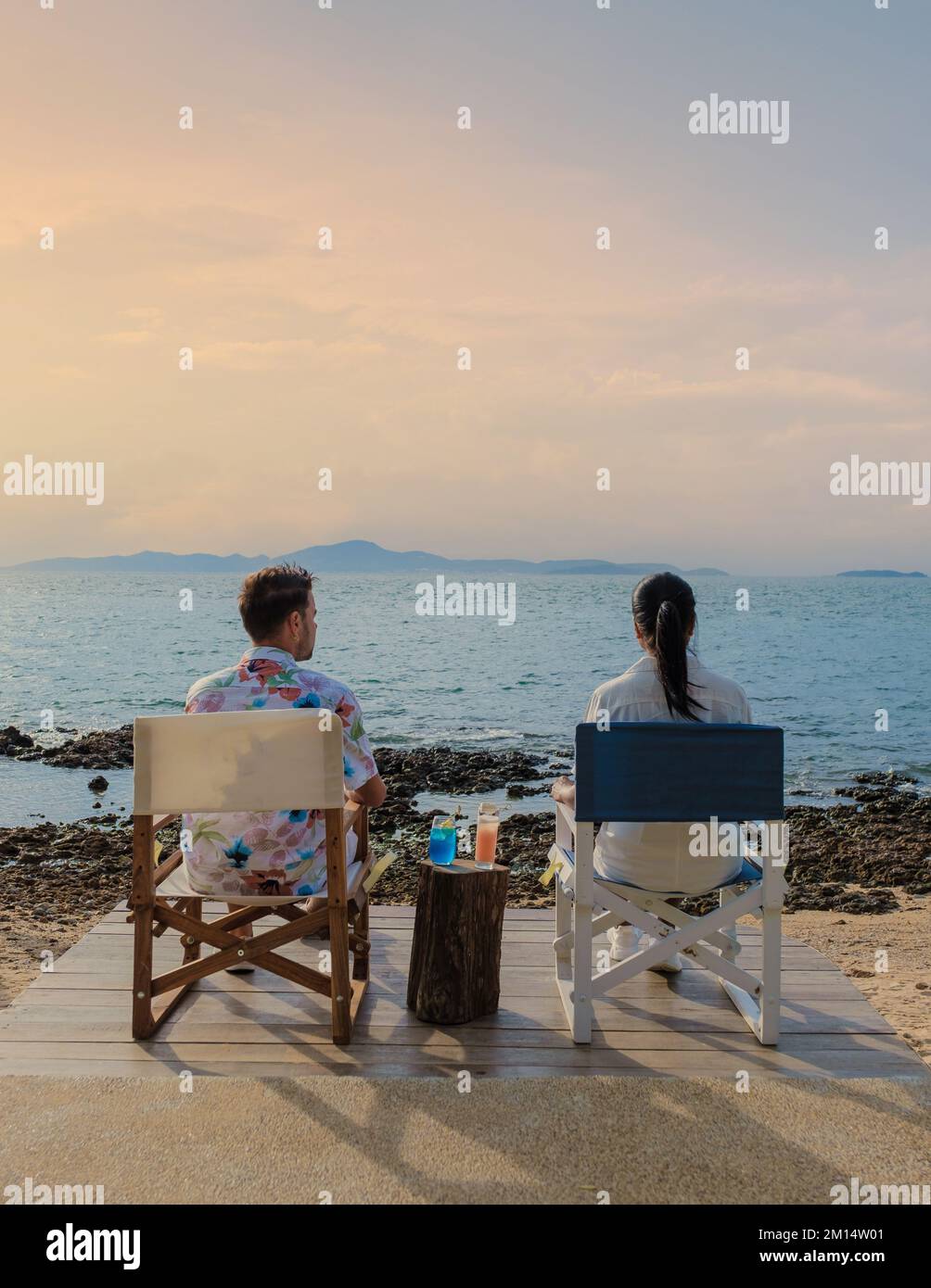 Ein Paar isst in einem Restaurant mit Blick auf das Meer von Pattaya Thailand zu Mittag, Mann und Frau essen bei Sonnenuntergang in einem Restaurant am Meer in Pattaya zu Abend Stockfoto