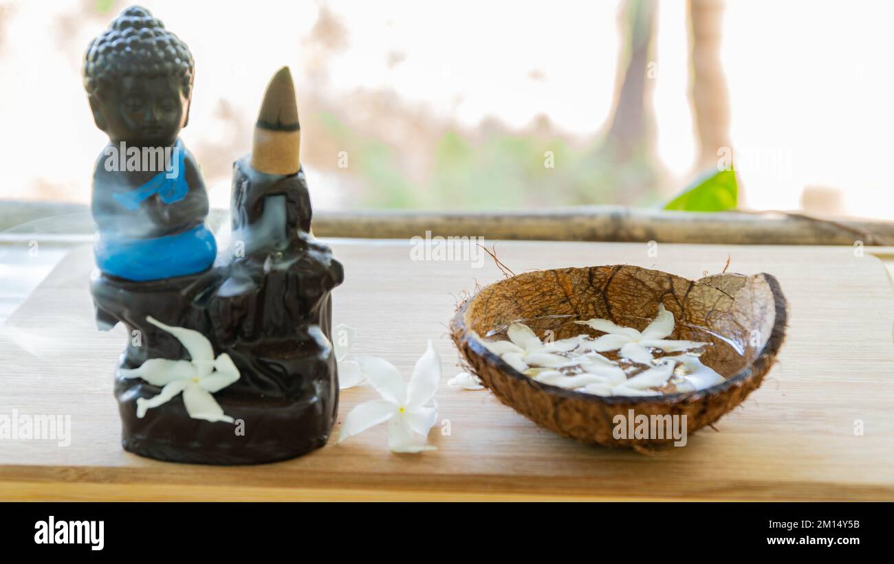 Dampfender Weihrauch auf einer Buddha-Figur mit Blumendekoration und orientalischen Traditionen Stockfoto