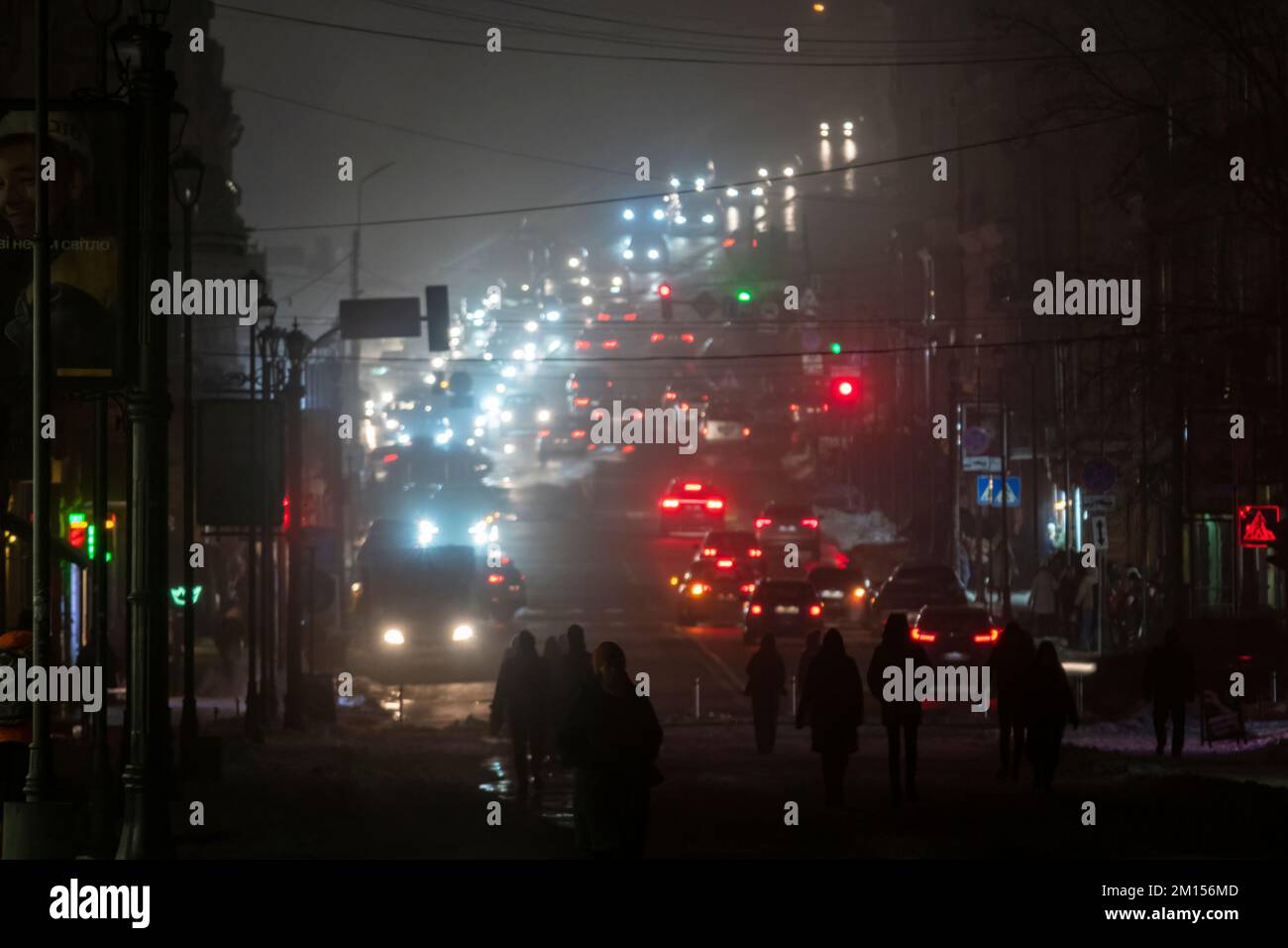 2022-12-08 Kiew, Ukraine. Nachtverkehr in der Stadt Kiew während Stromausfall. Fußgänger, Autos und Stadtlichter im Nebel Stockfoto