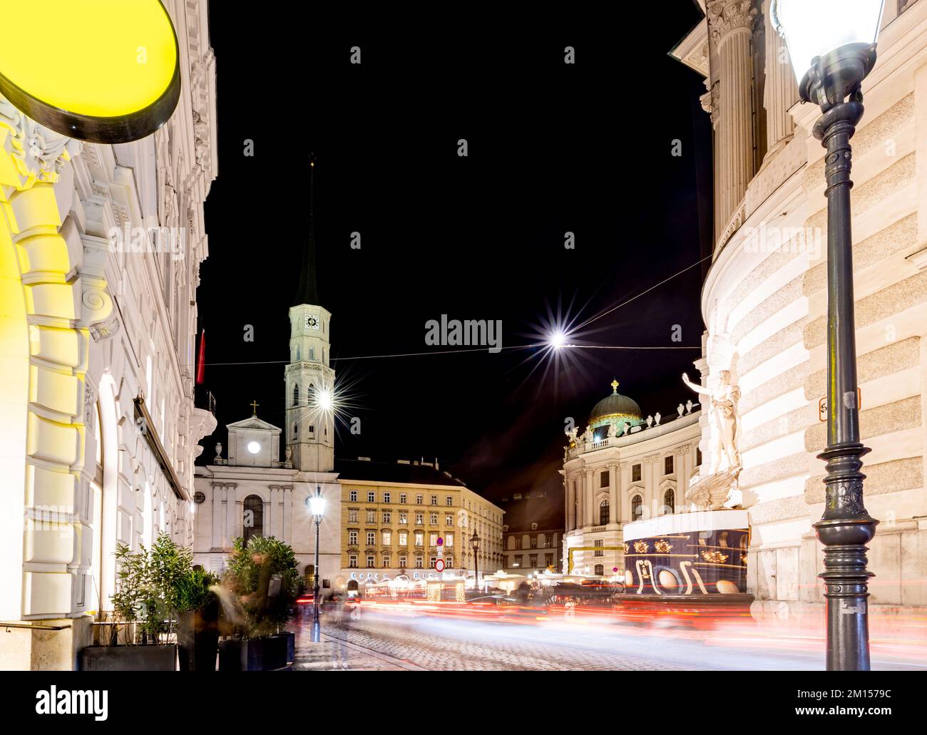 Die Erzengel-Michael-Kirche in Wien bei Nacht. Der Michaelerplatz und sein Weihnachtsmarkt in Wien. Stockfoto