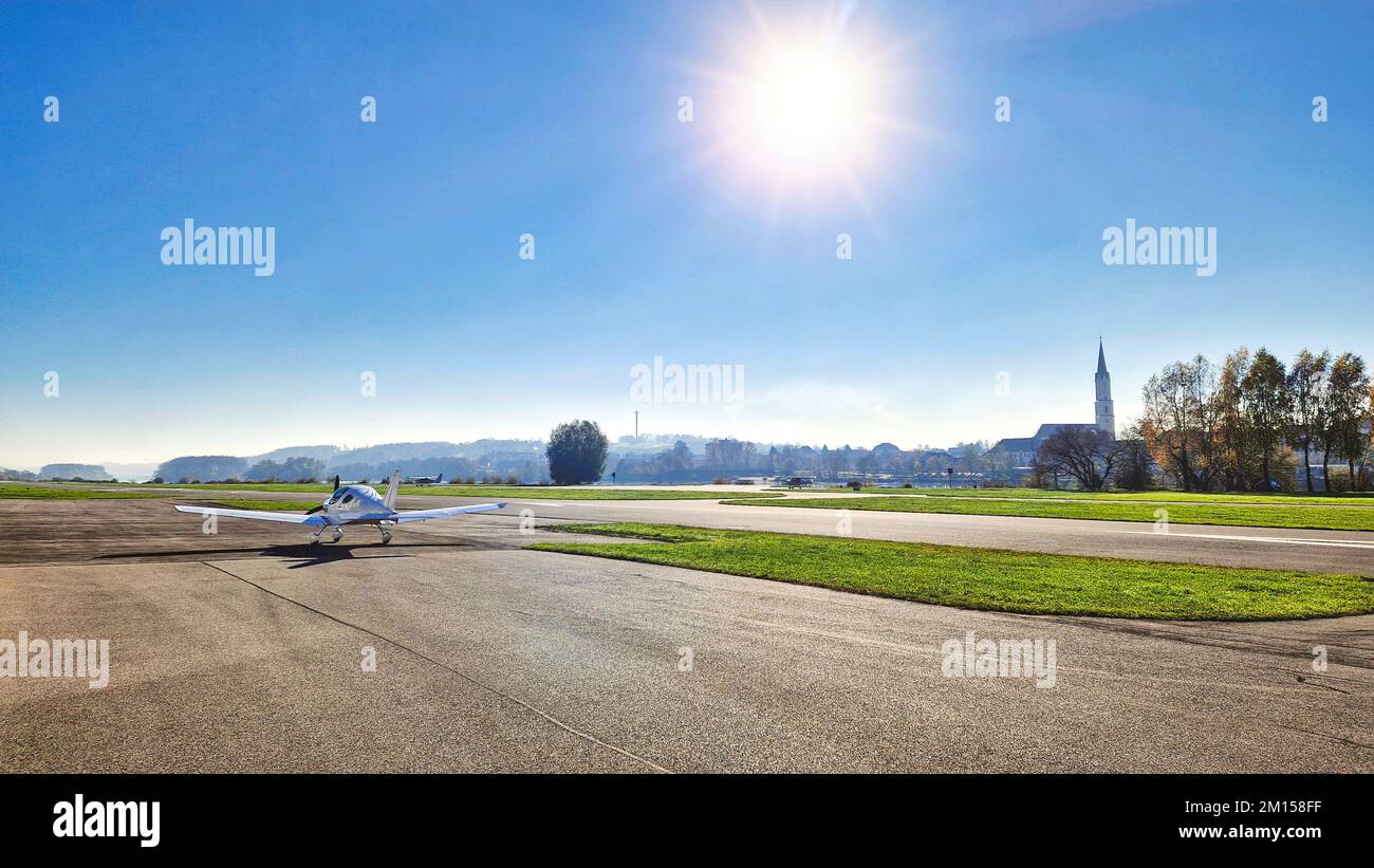 An einem sonnigen Tag steht ein Kleinstadt mit einem Kirchturm im Hintergrund auf der Landebahn auf einem Flugplatz Stockfoto