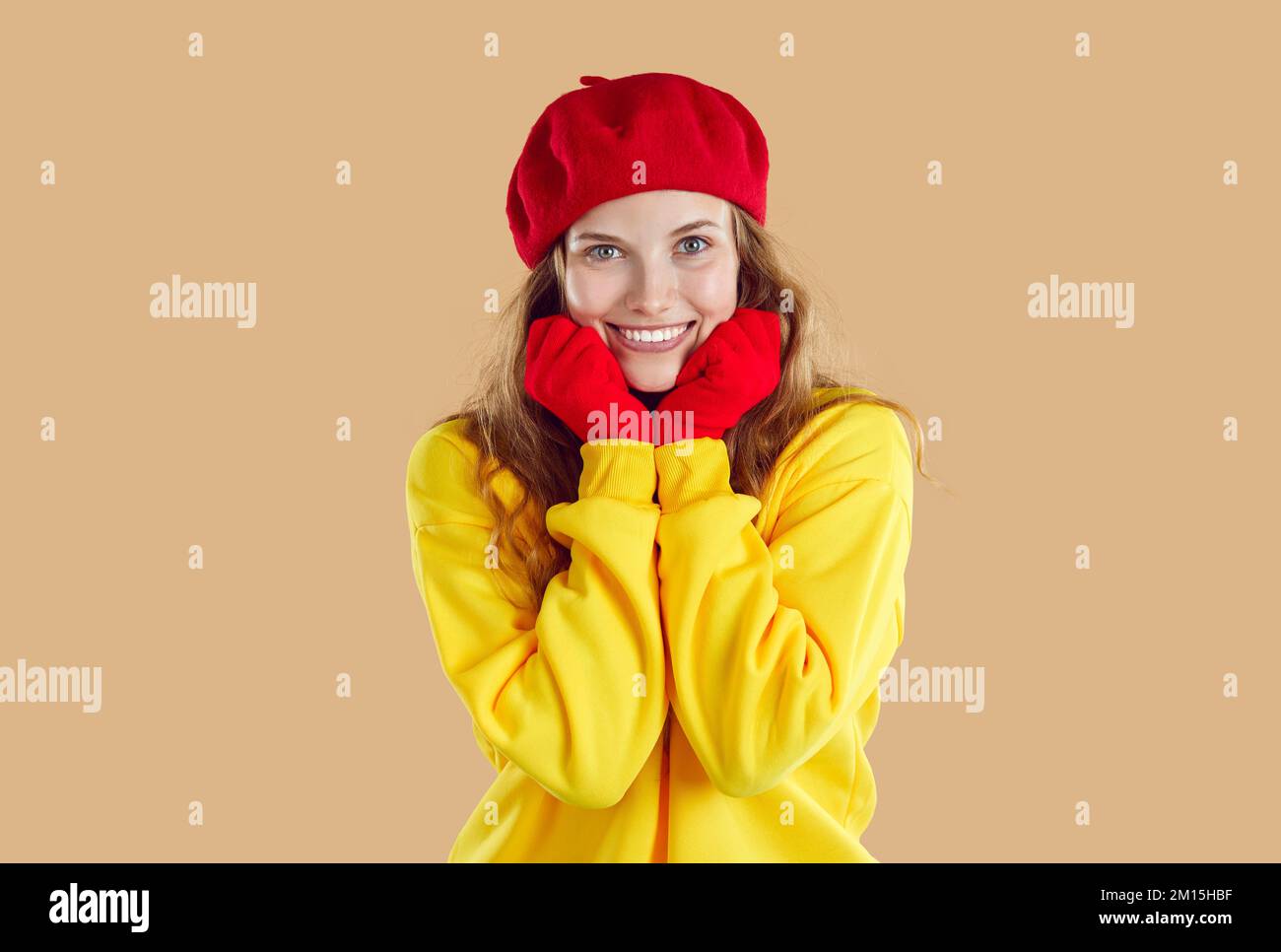 Porträt einer süßen lächelnden jungen Frau in Herbstkleidung, die ihre Hände nahe ihrem Gesicht hält. Stockfoto