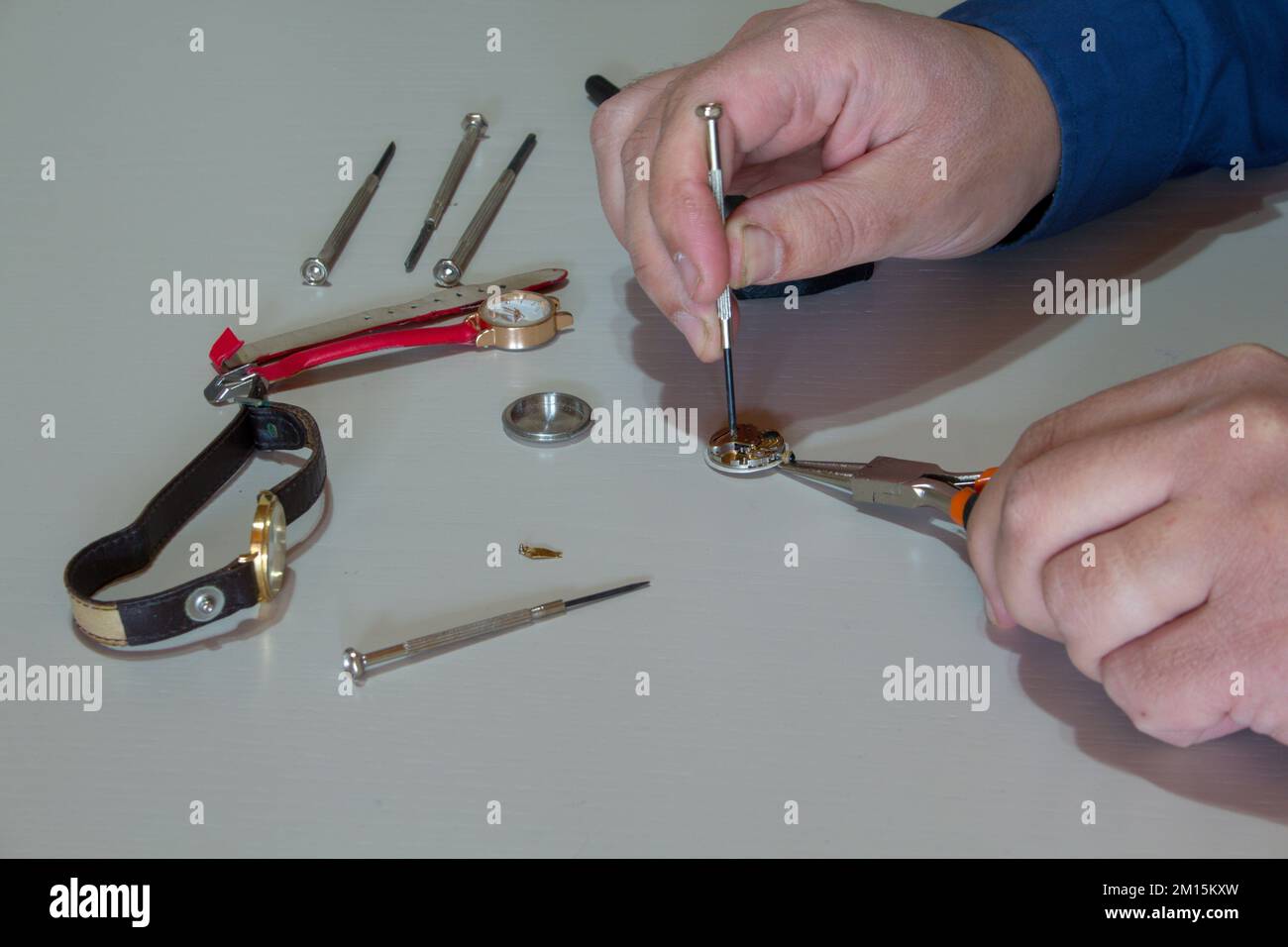 Bild der Hände eines Goldschmieds, der eine kleine Armbanduhr mit den Werkzeugen des Handwerks repariert. Uhrmacher bei der Arbeit. Stockfoto