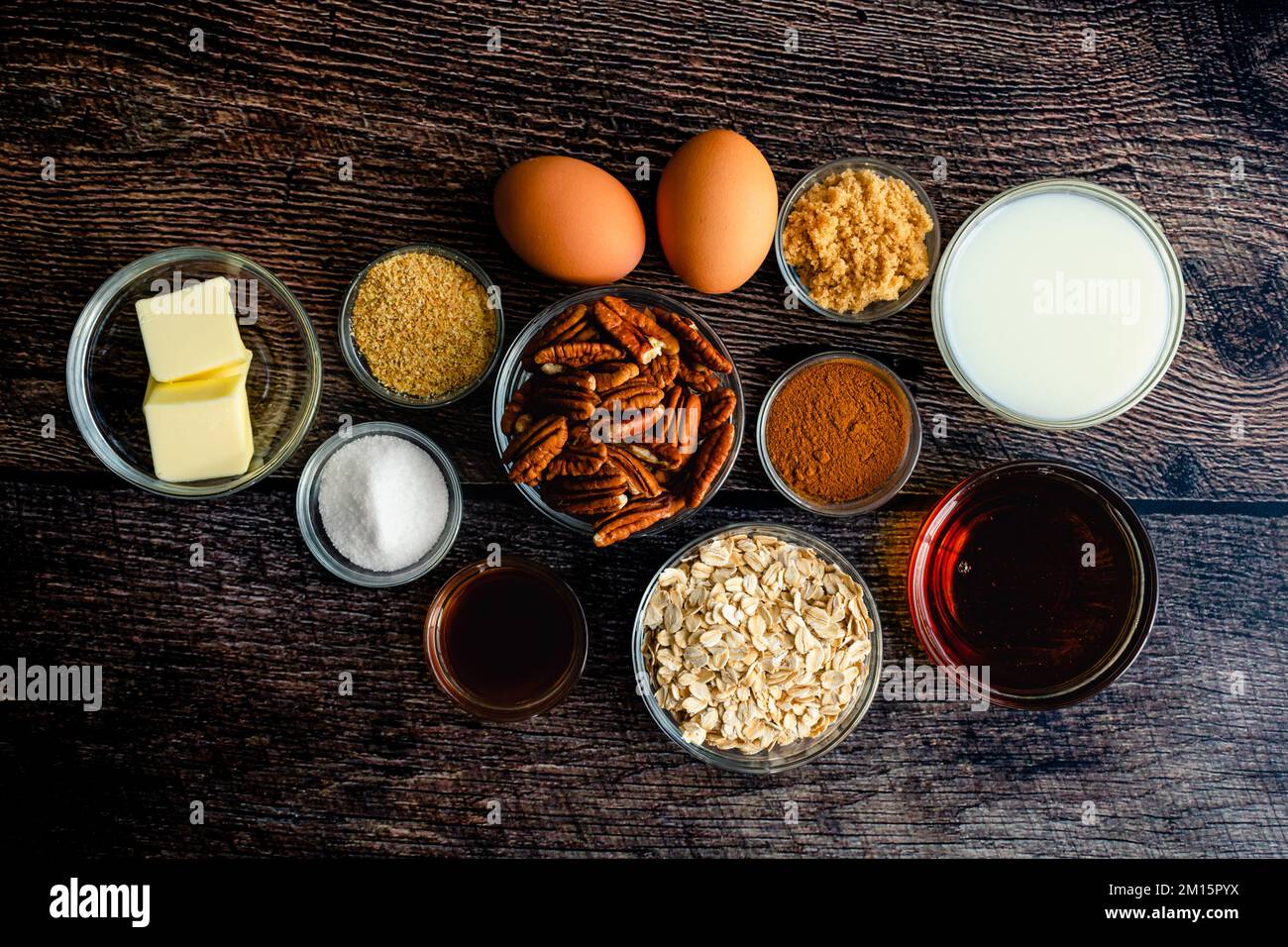 Pekannuskuchen Backoatmeal Zutaten flach auf einem Holztisch: Gerollte Haferflocken, Pekannahälften und andere Zutaten für ein gesundes Frühstücksgericht Stockfoto