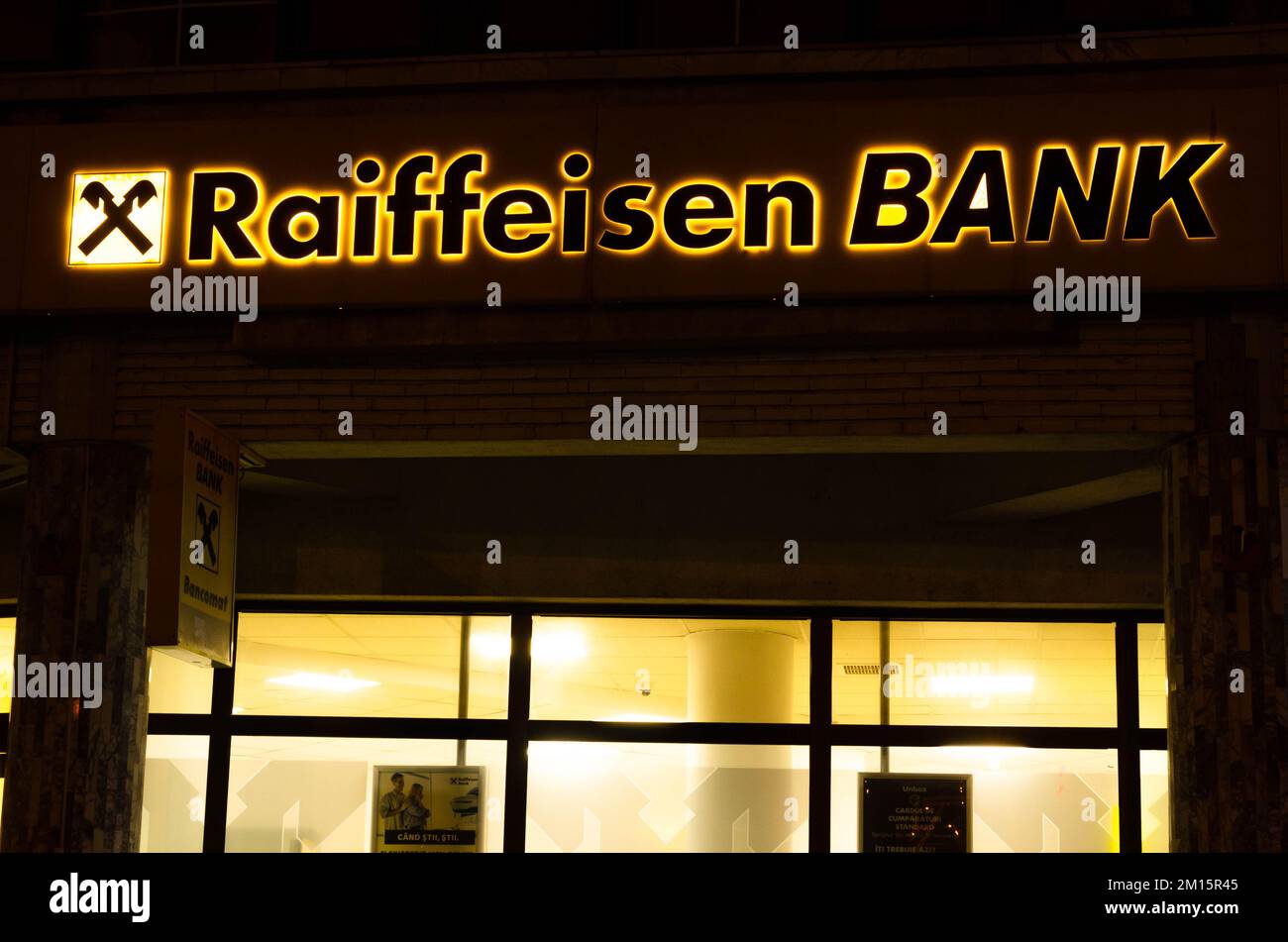 Bukarest, Rumänien - 10. Dezember 2022: Schild und Logo der österreichischen Bank Raiffeisenbank Bank am Abend auf der Straße in Bukarest Stockfoto