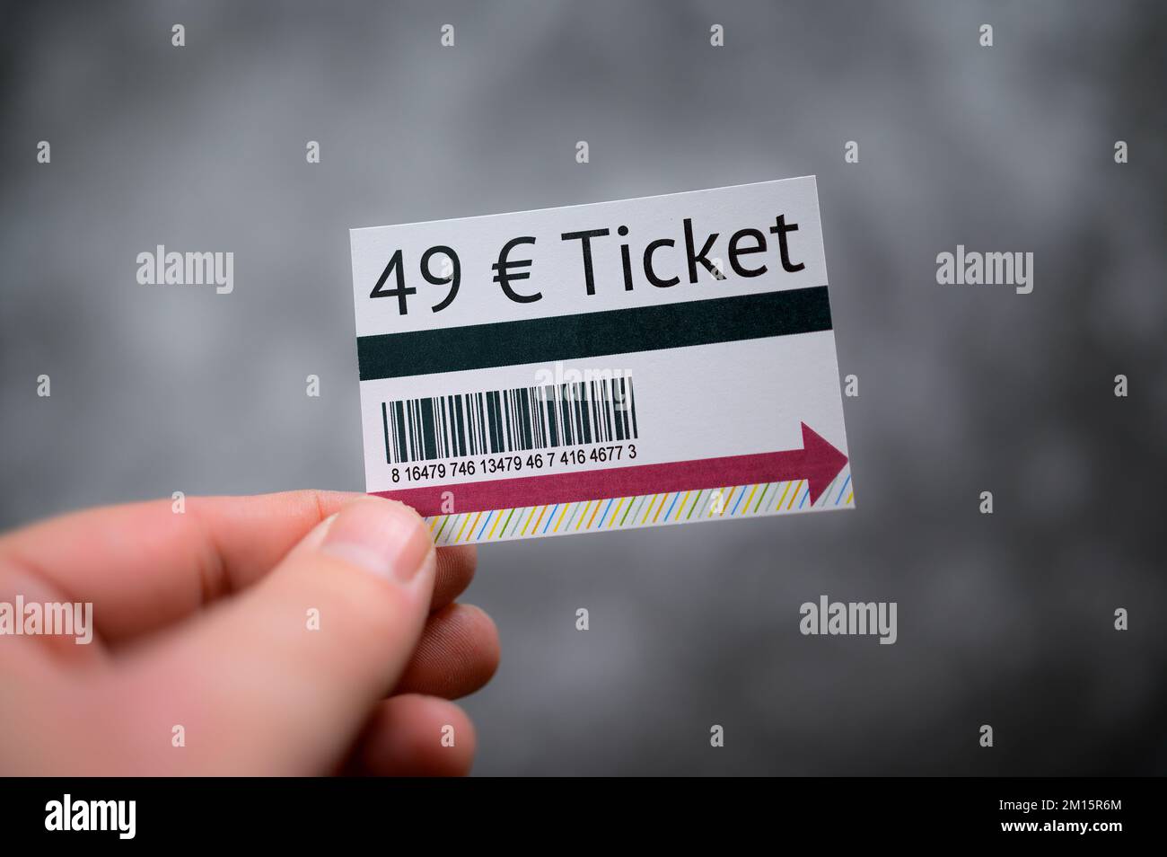 Hand hält ein neues deutsches 49-Euro-Ticket-Modell vor grauem Hintergrund Stockfoto