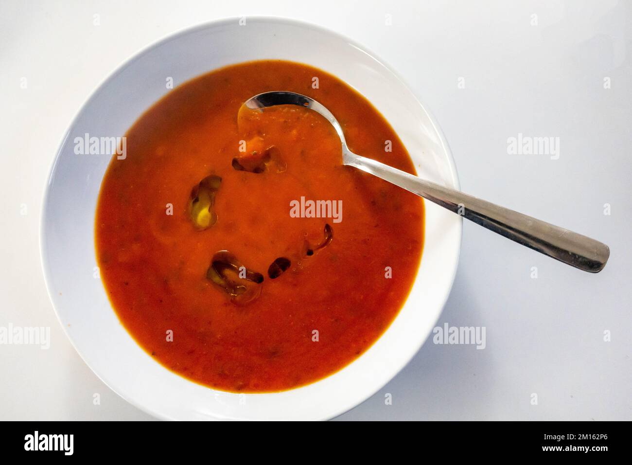 Nahaufnahme einer frischen Tomatensuppe mit Olivenöl in einer weißen Schüssel Stockfoto