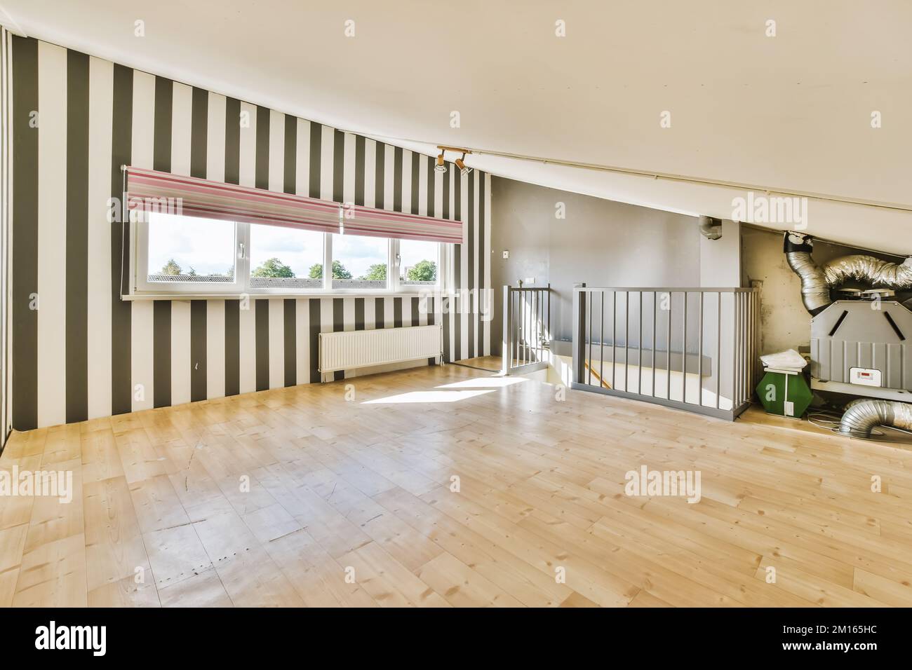 Ein leeres Wohnzimmer mit Holzfußboden und gestreiften Tapeten an den Wänden in Schwarz-Weiß-Streifen Stockfoto