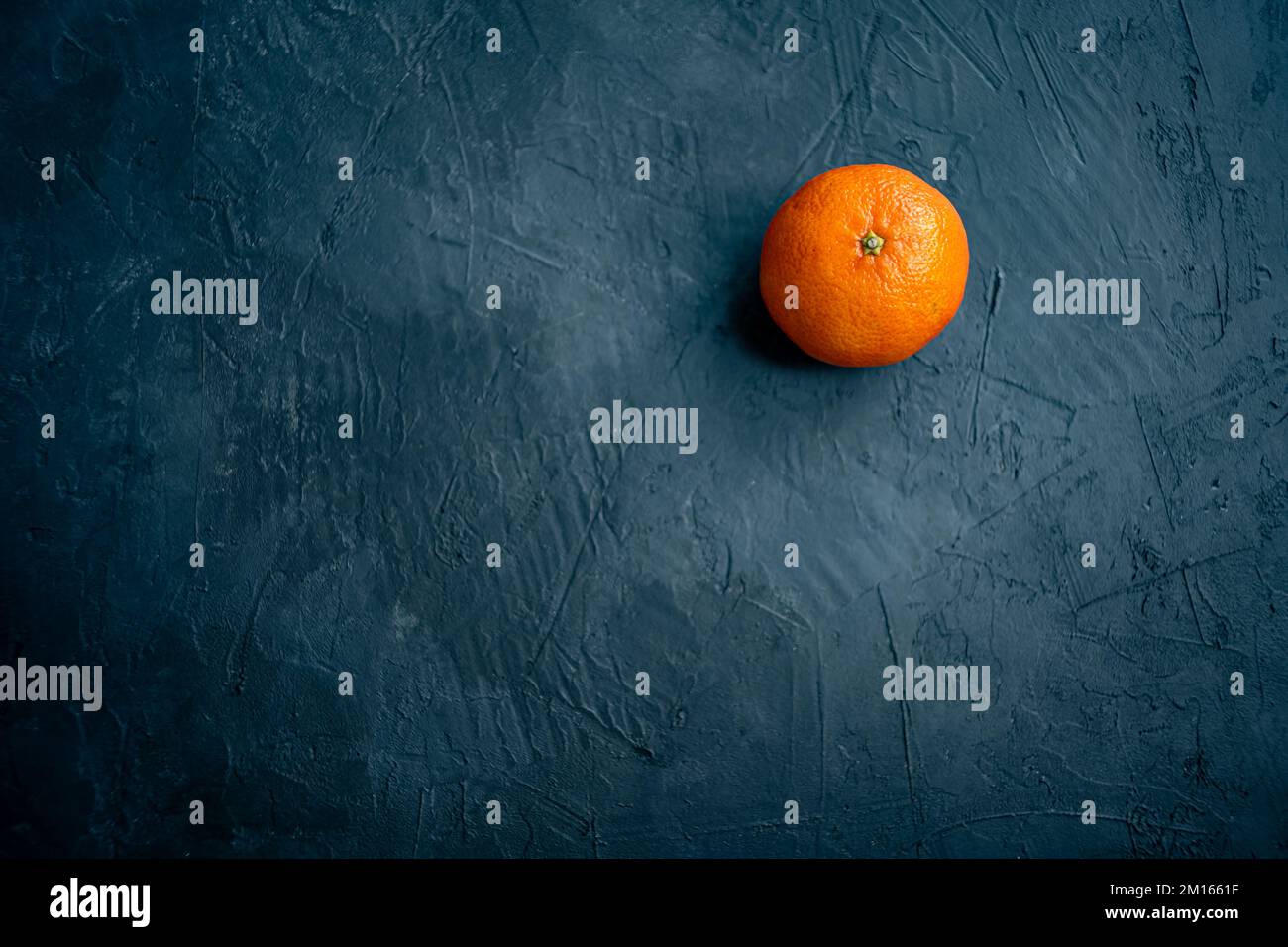 Isolierte Mandarinenfrucht auf dunklem Schieferhintergrund. Ansicht von oben mit Kopierbereich für Text Stockfoto