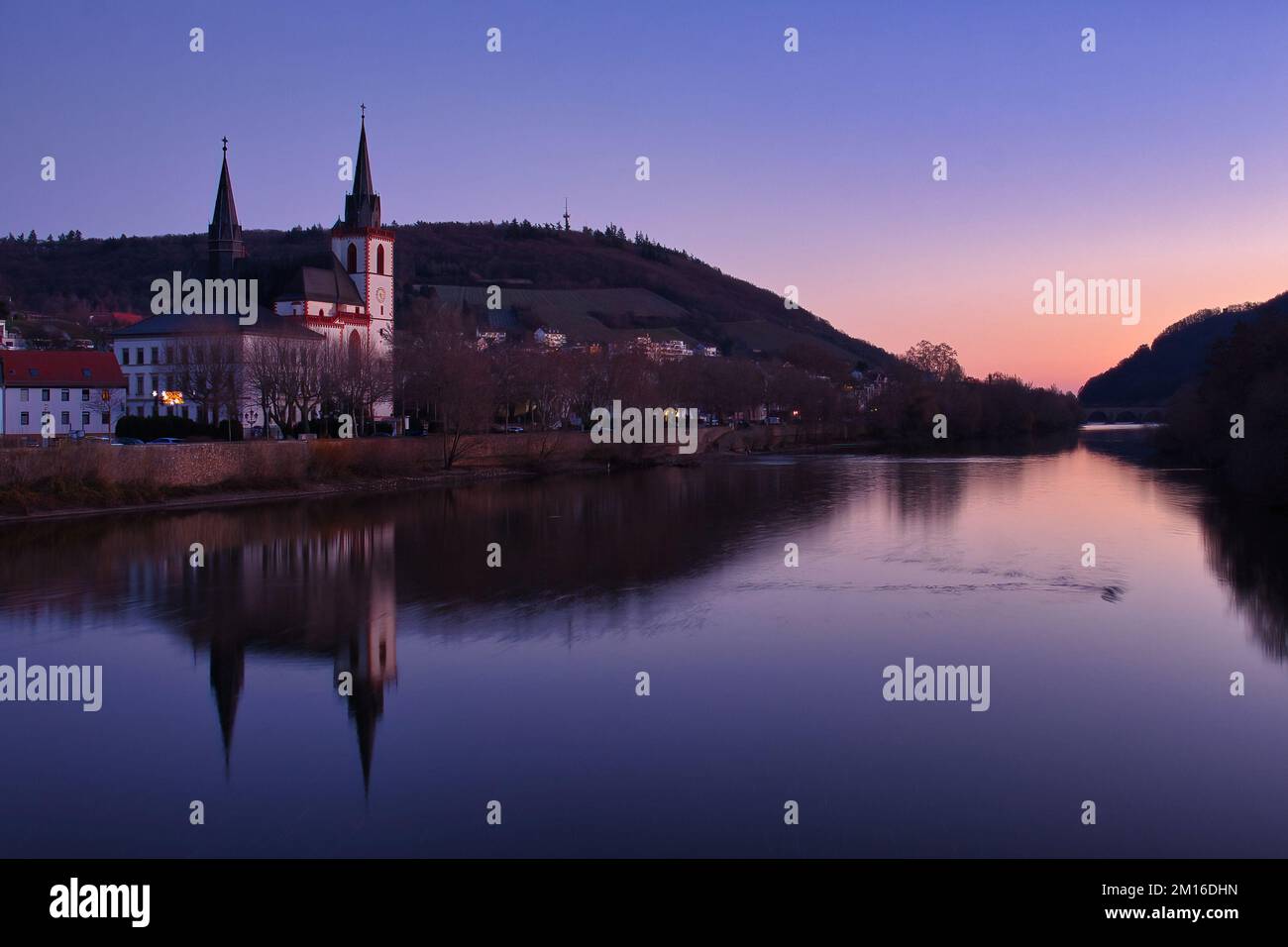 Bingen am Rhein, Deutschland - 10. Januar 2021: Basilika St. Martin und andere Gebäude und ihre Reflexionen im Rhein im bunten Winter Stockfoto