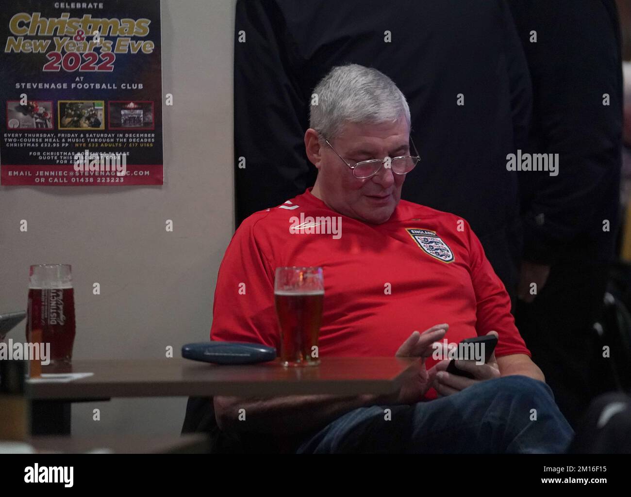 Ein englischer Fan schaut auf sein Handy in der 76 Lounge im Lamex Stadium, Stevenage, während er eine Vorführung des Viertelfinalspiels der FIFA-Weltmeisterschaft zwischen England und Frankreich sieht. Foto: Samstag, 10. Dezember 2022. Stockfoto